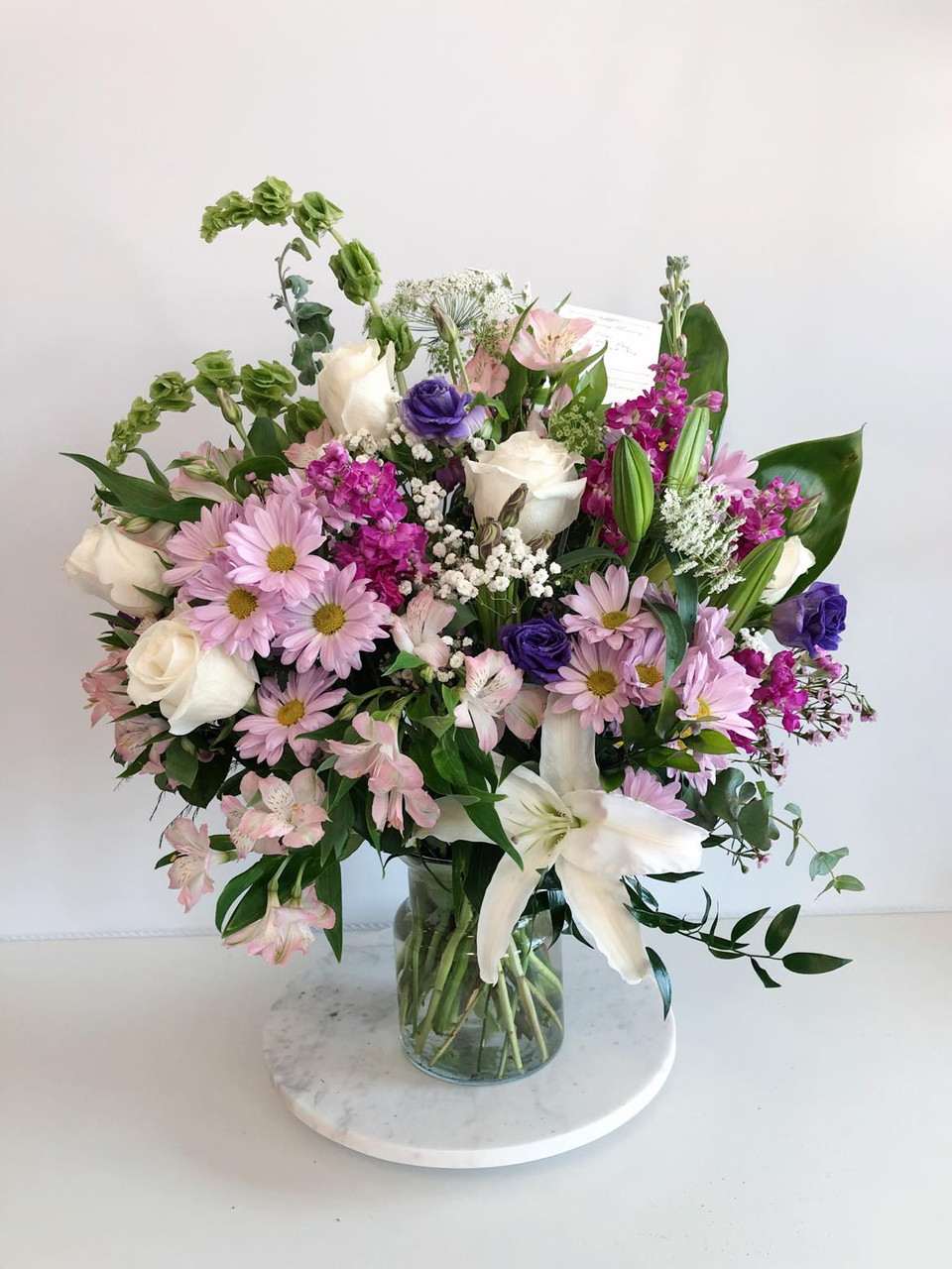 Mixed bouquet of pink, white, and purple flowers in a glass vase