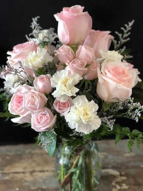 Pink roses and white carnations arranged in a glass vase