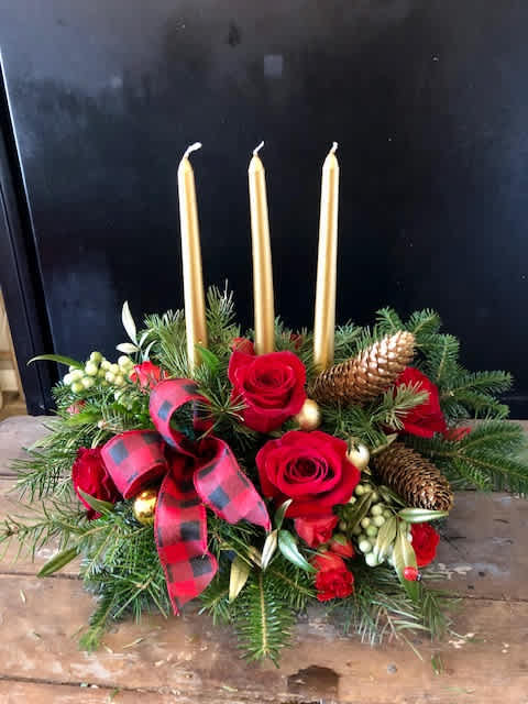 Holiday centerpiece with red roses, gold candles, and pinecones