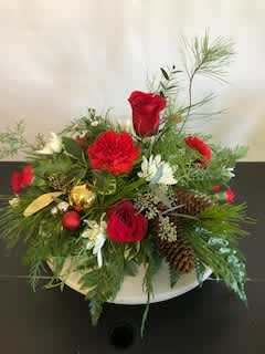 Red roses and carnations arranged with pinecones in a white container