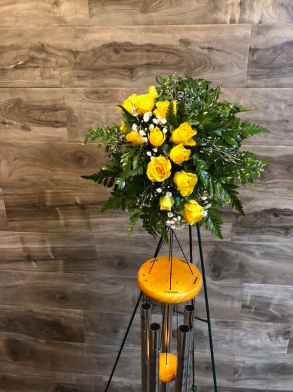 Yellow rose arrangement on a tall stand with greenery and white filler flowers