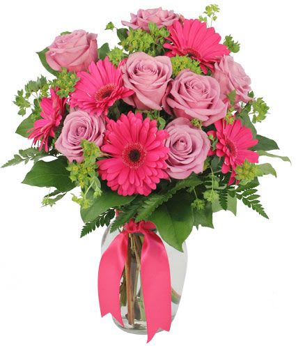 Pink roses and gerbera daisies in a glass vase with a ribbon