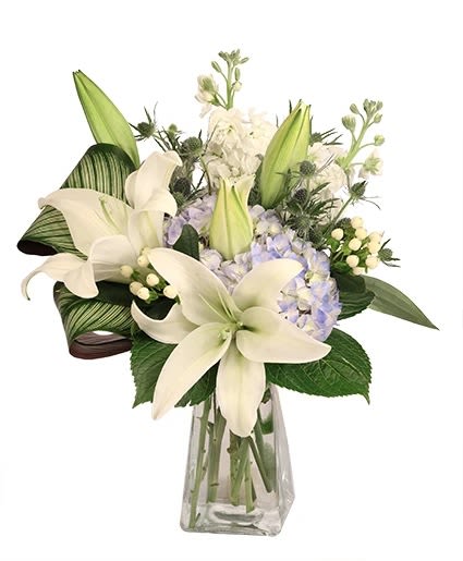 White lilies and pale hydrangeas in a clear glass vase