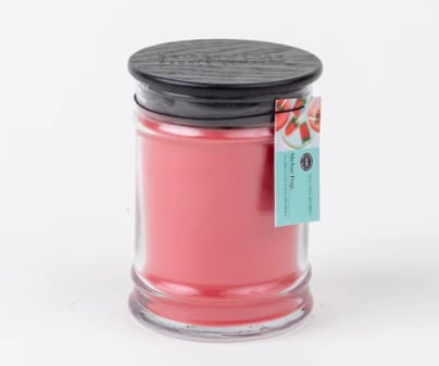 Pink candle in a clear glass jar with a black lid