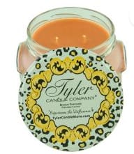 Orange candle in a glass jar with a decorative label