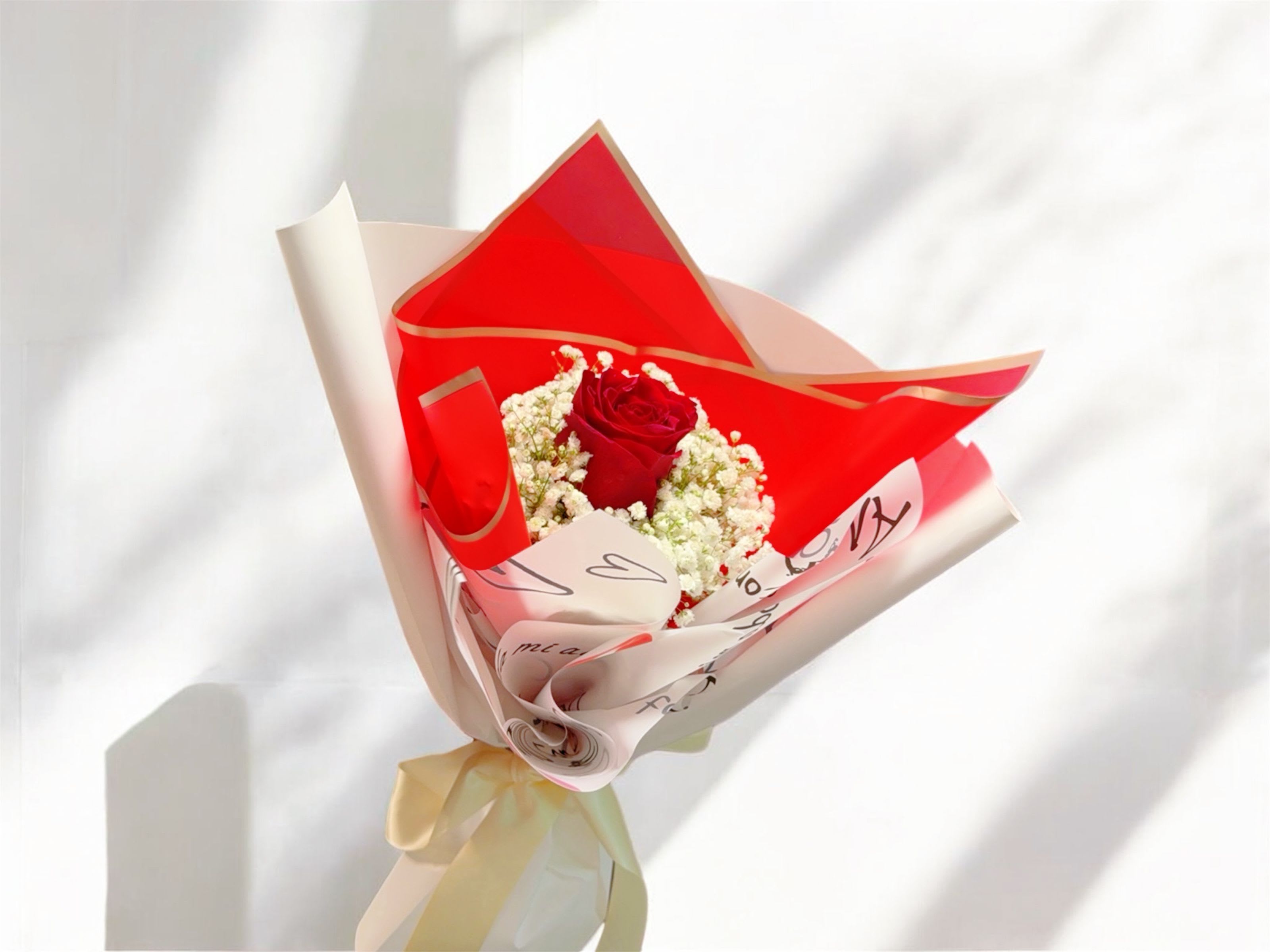 Single red rose bouquet wrapped in red and white paper