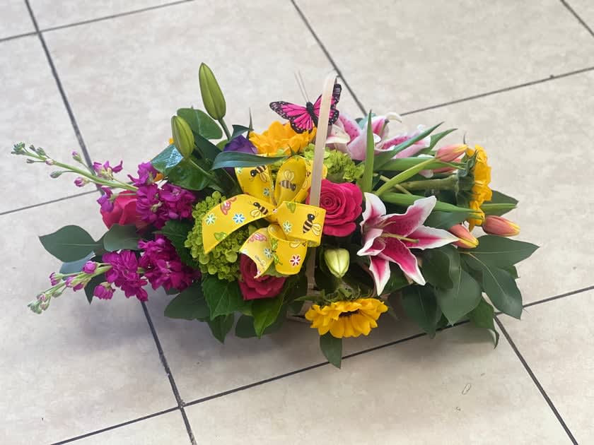 Colorful mixed flower basket with lilies, roses, and a yellow ribbon