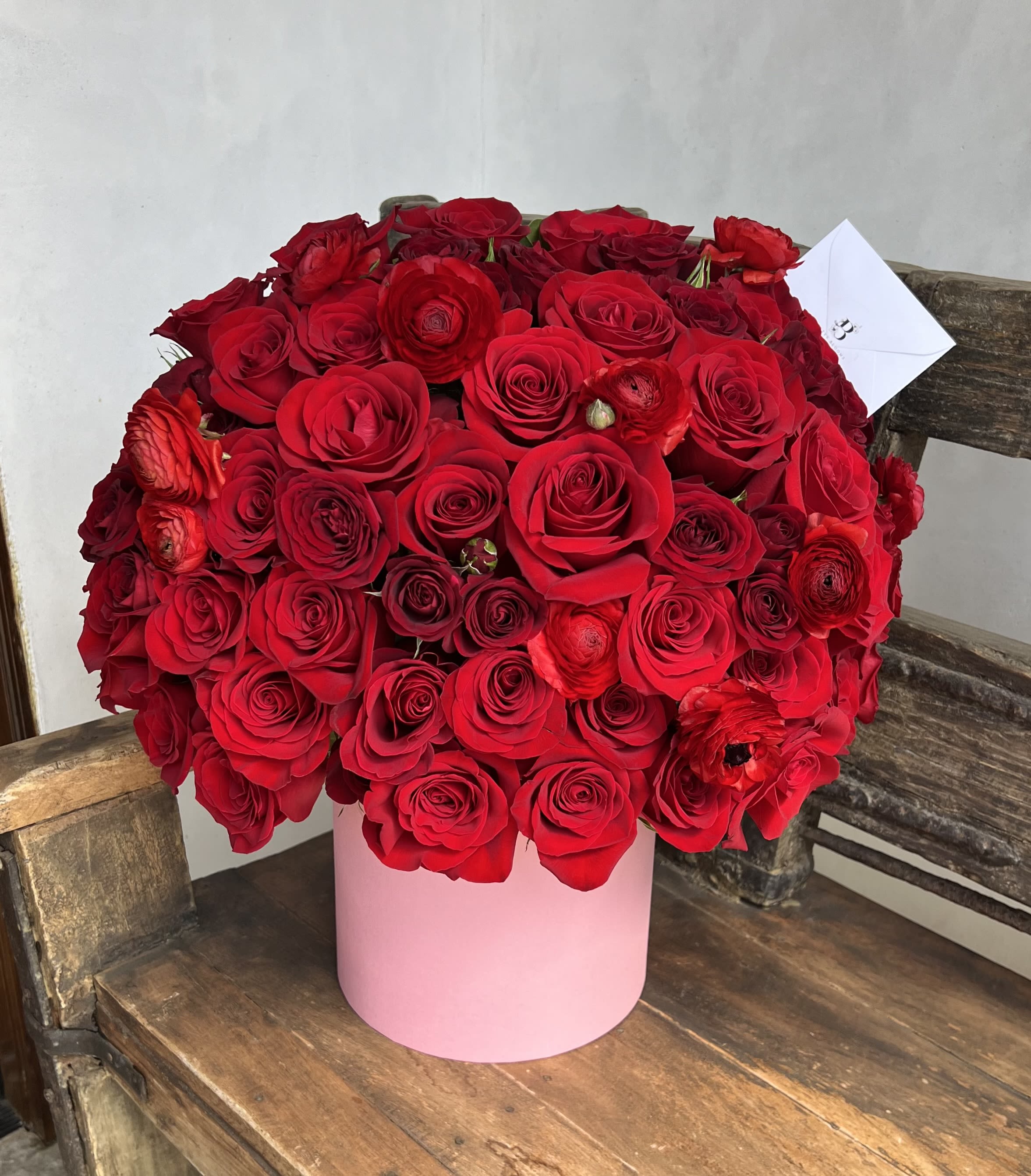 Large bouquet of red roses in a pink cylindrical box