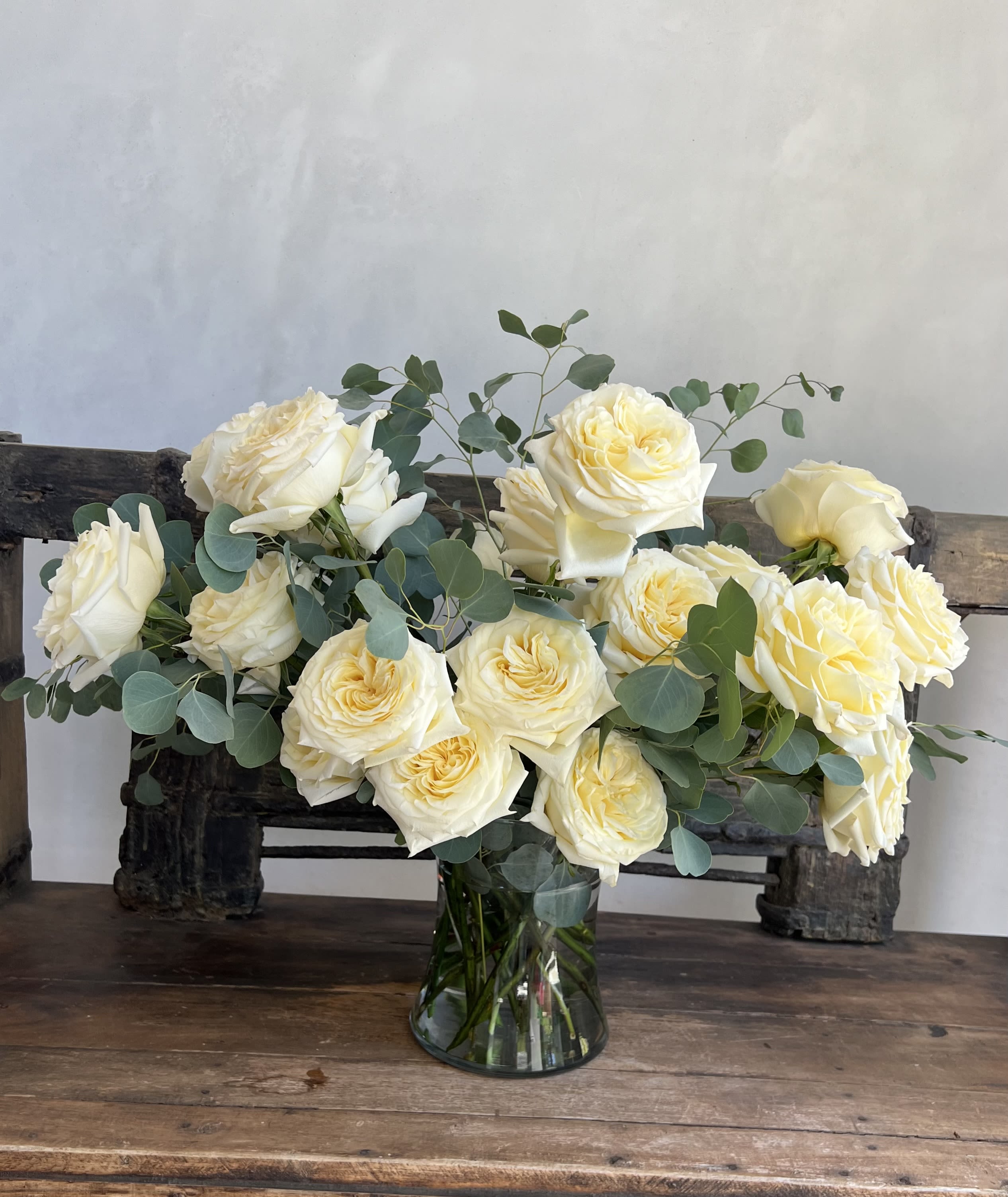 Cream roses arranged in a glass vase with eucalyptus