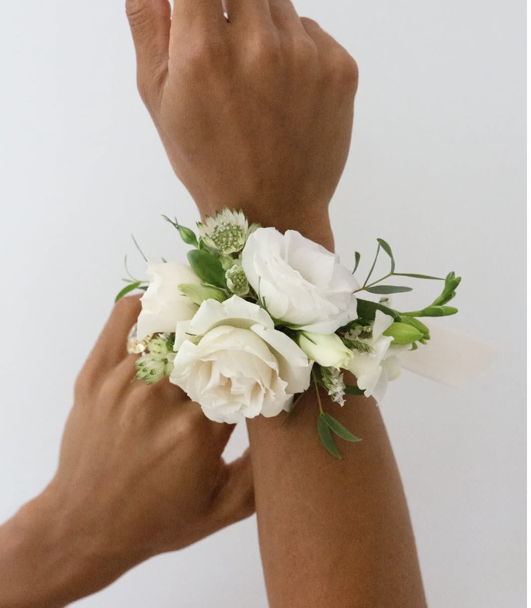 White floral wrist corsage on a person's wrist