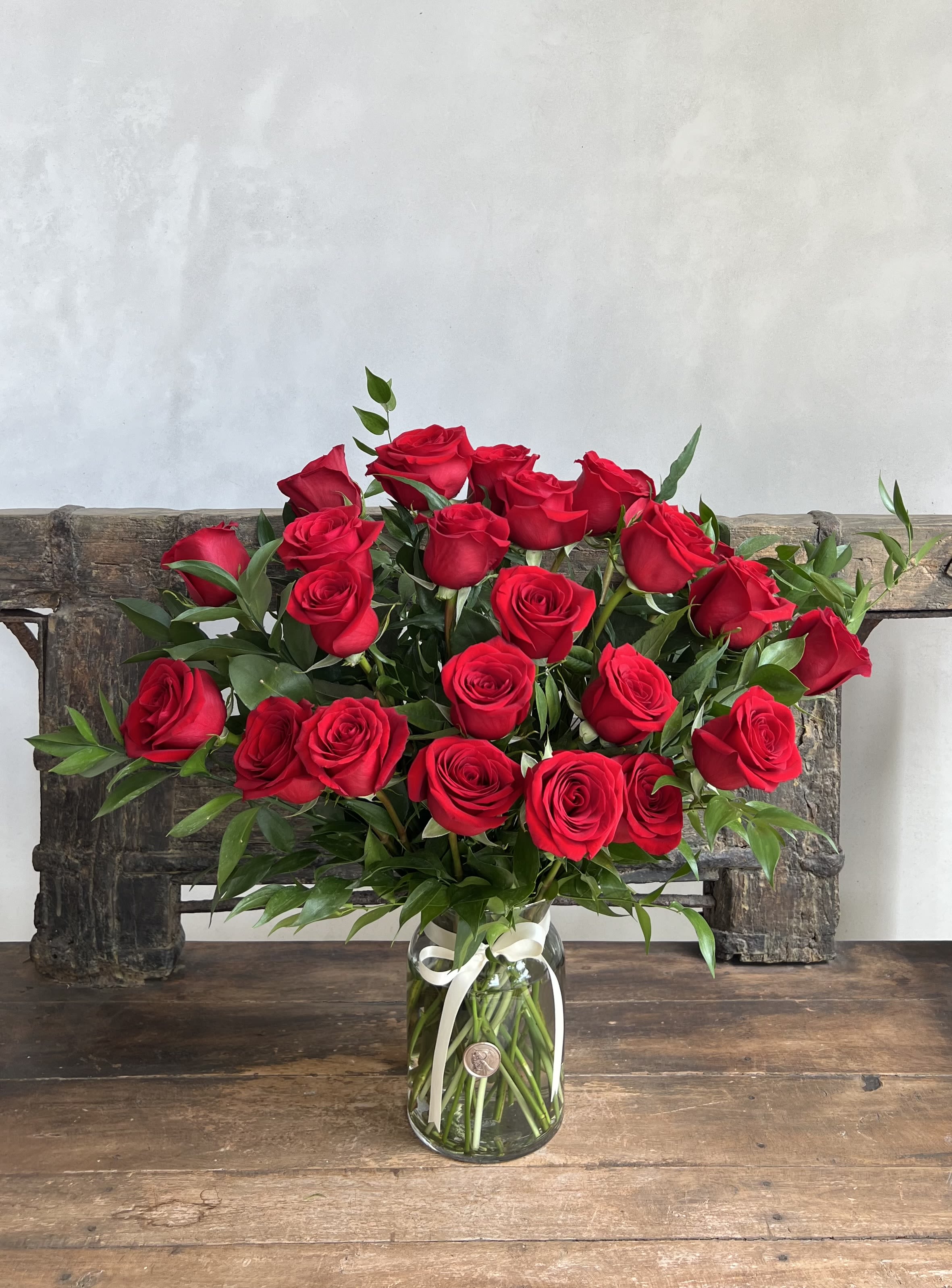 Bouquet of red roses in a clear glass vase with a white ribbon