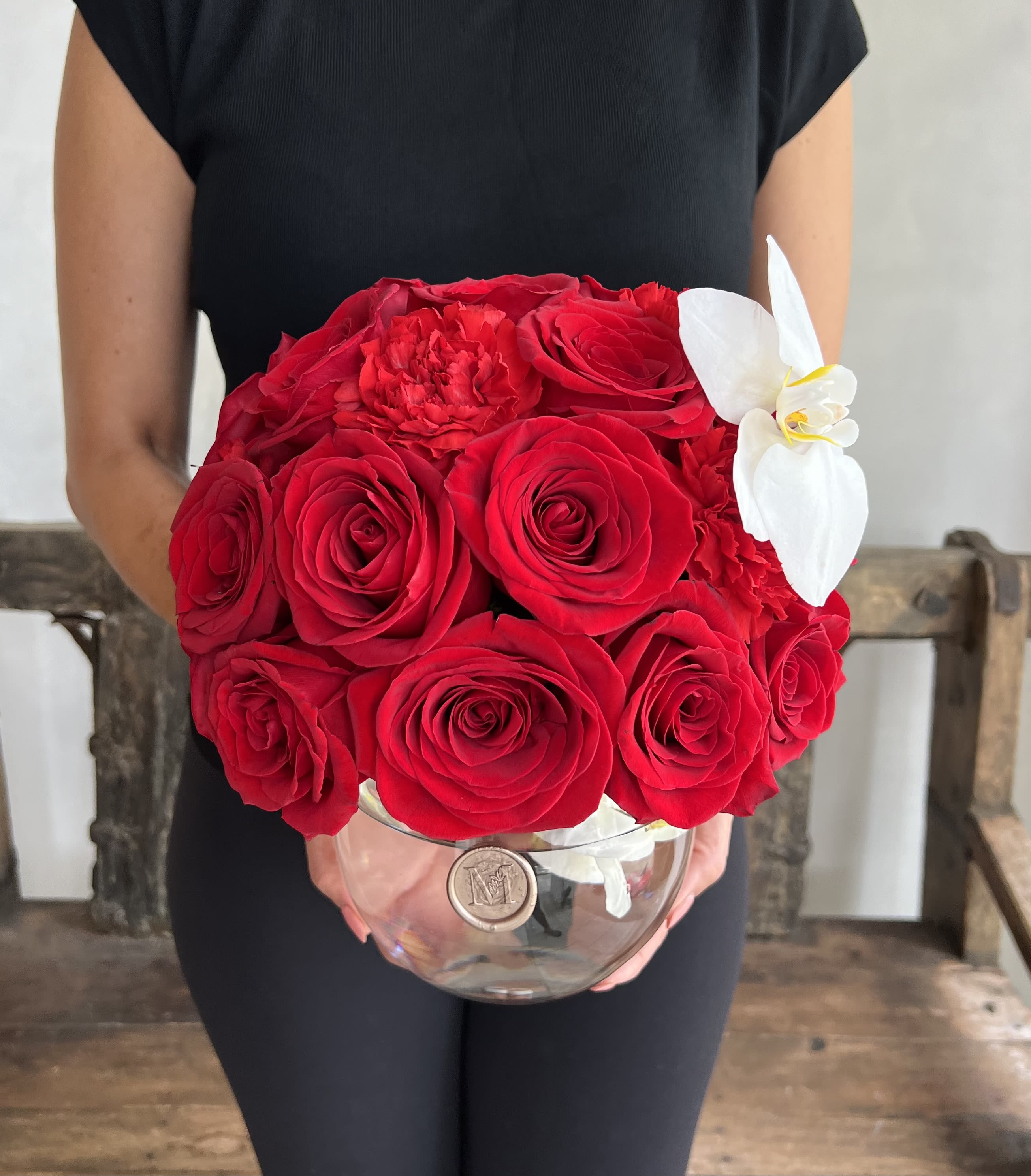 Red rose bouquet with a white orchid in a clear glass vase
