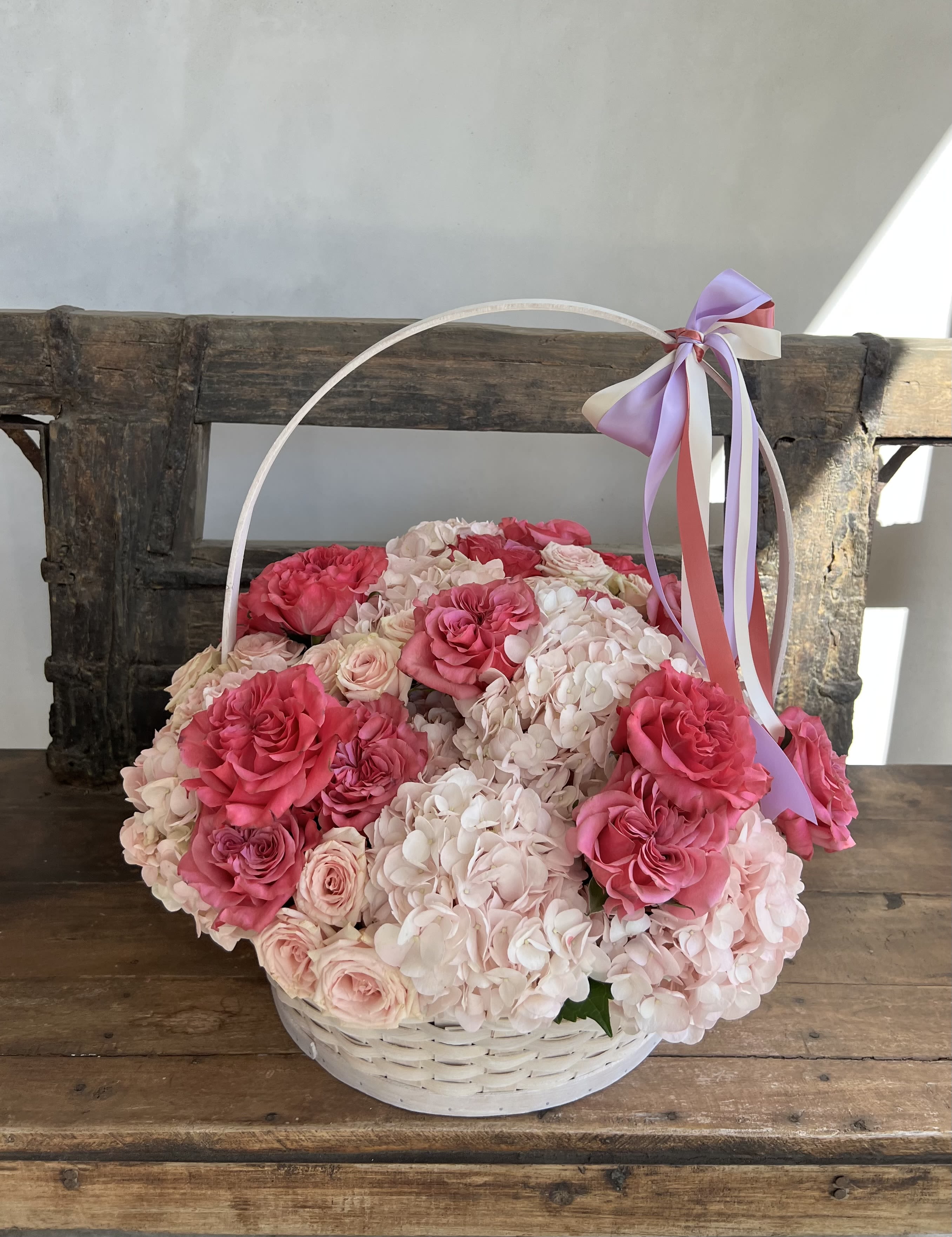 Basket of pink roses and pale hydrangeas with a ribbon handle