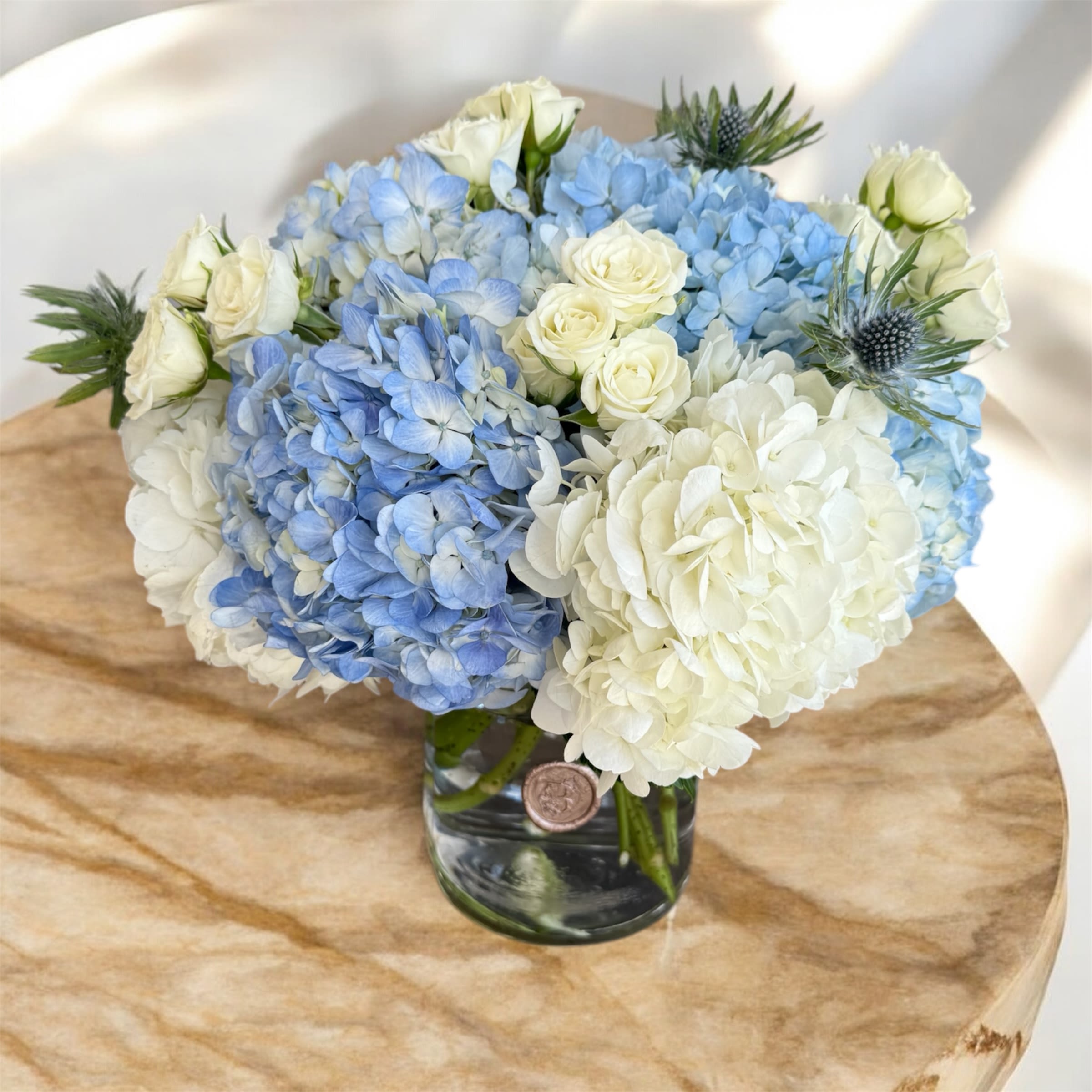 Blue and white hydrangea bouquet with white roses in a glass vase