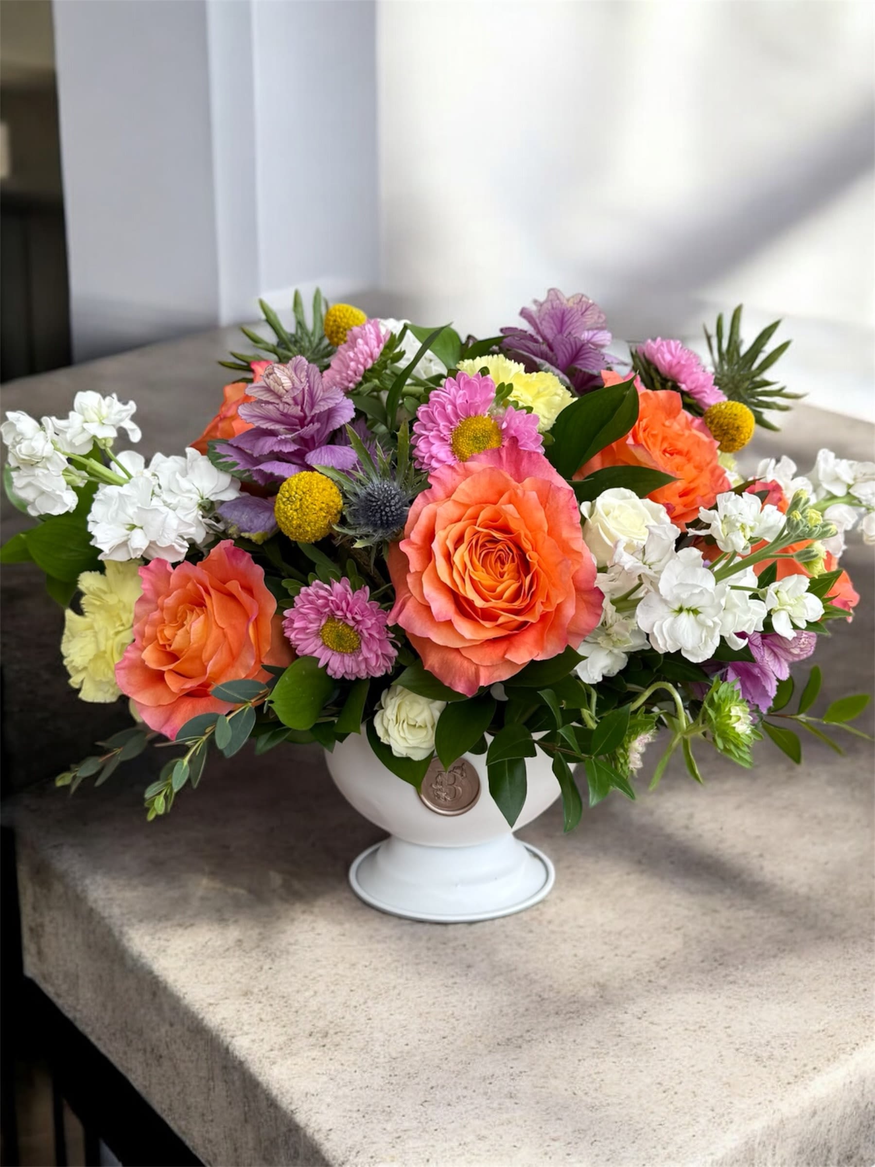 Colorful mixed flower arrangement in a white pedestal vase