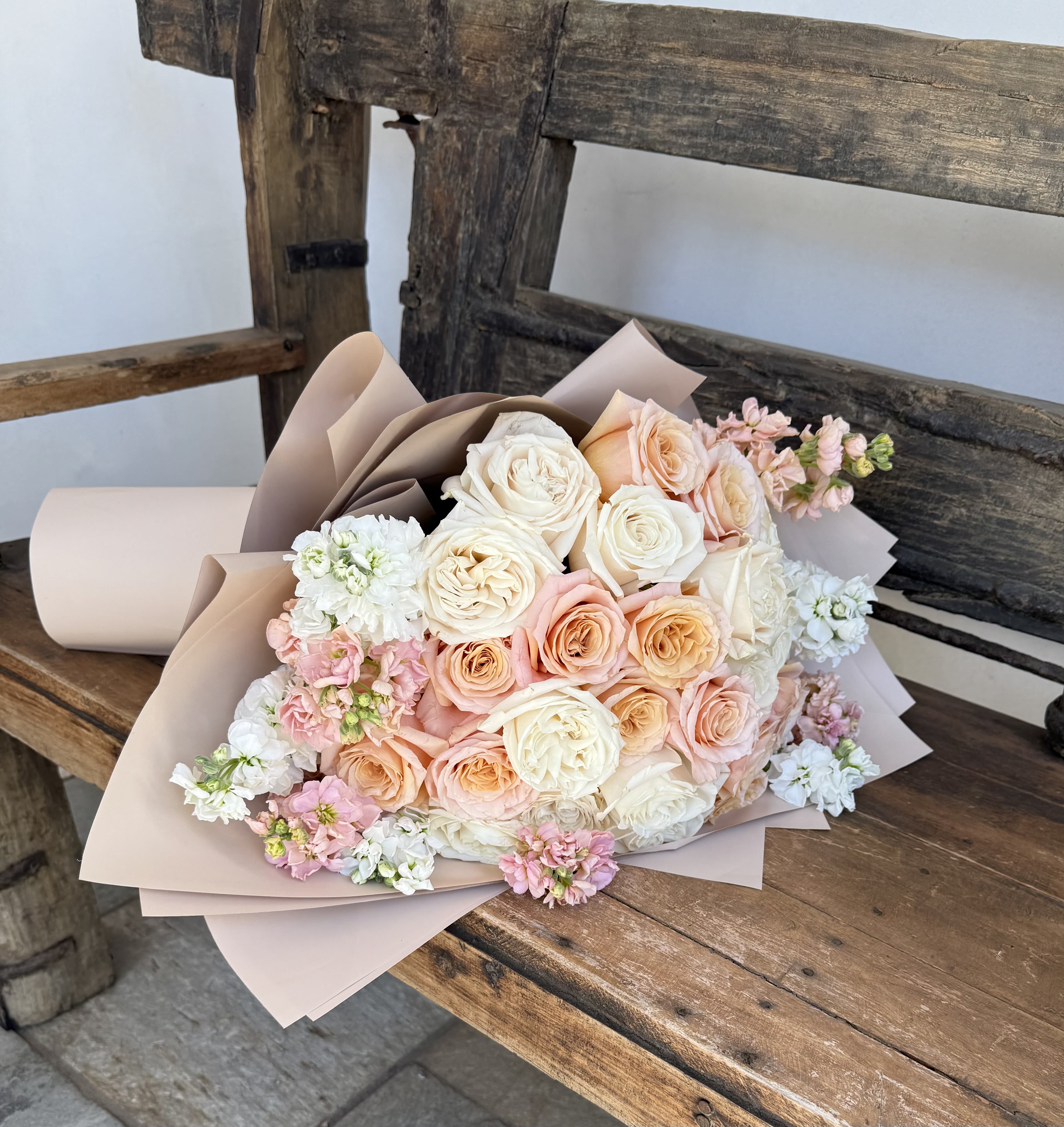Bouquet of blush, peach, and white roses with small pink and white filler flowers