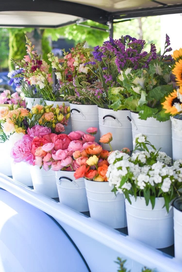 Buckets of colorful cut flowers arranged on a market display