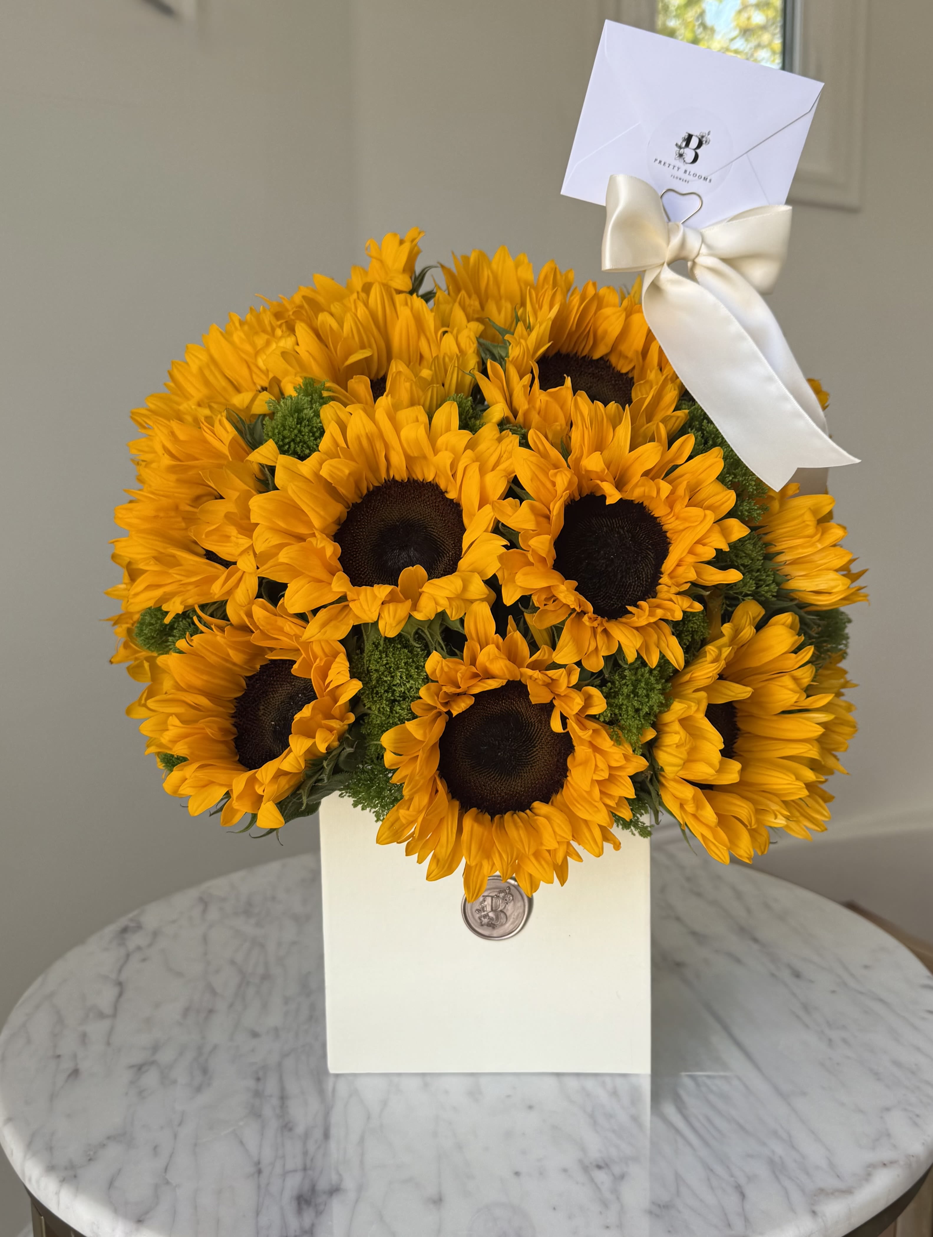 Bouquet of bright yellow sunflowers in a white gift box with a ribbon