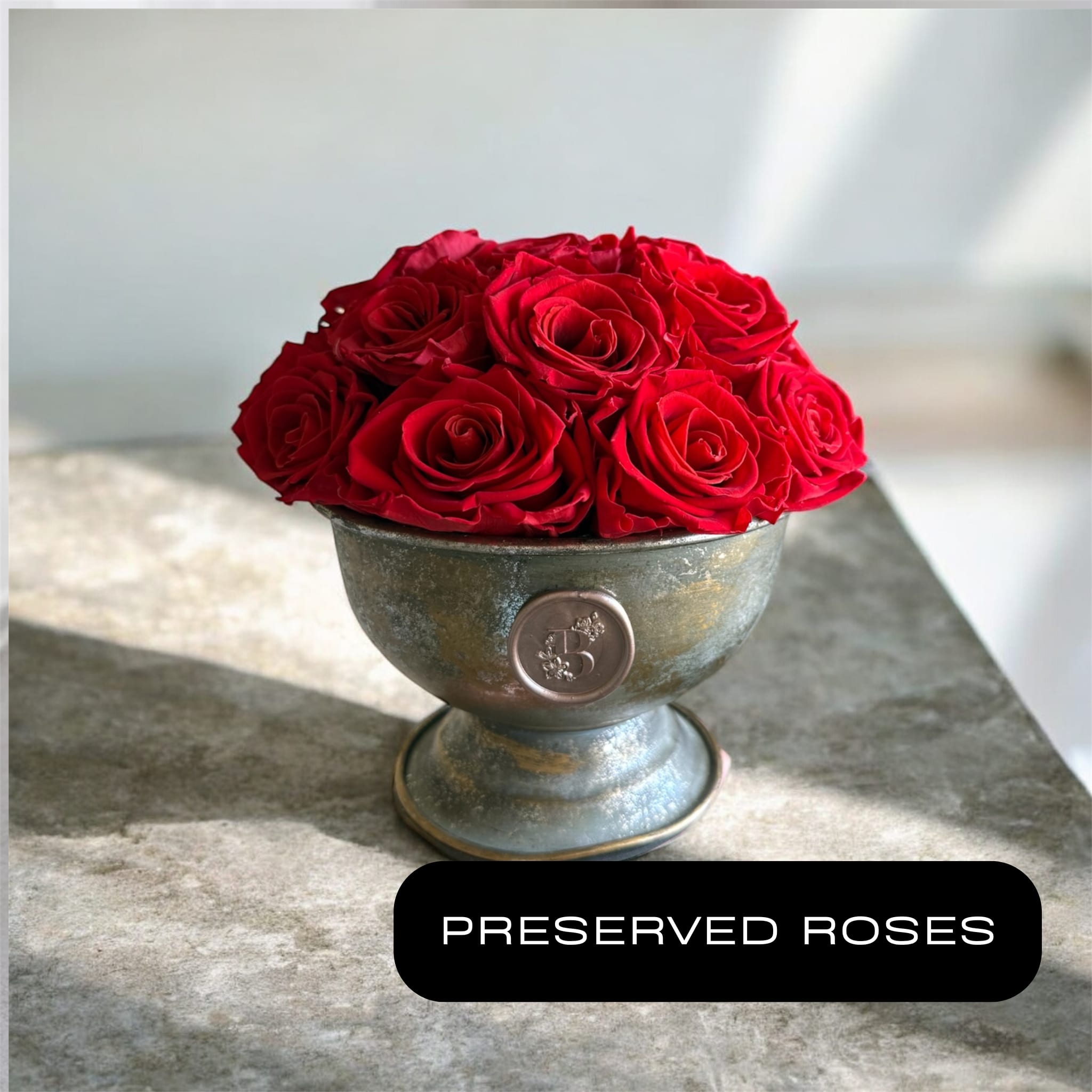 Red roses arranged in a small metal pedestal bowl