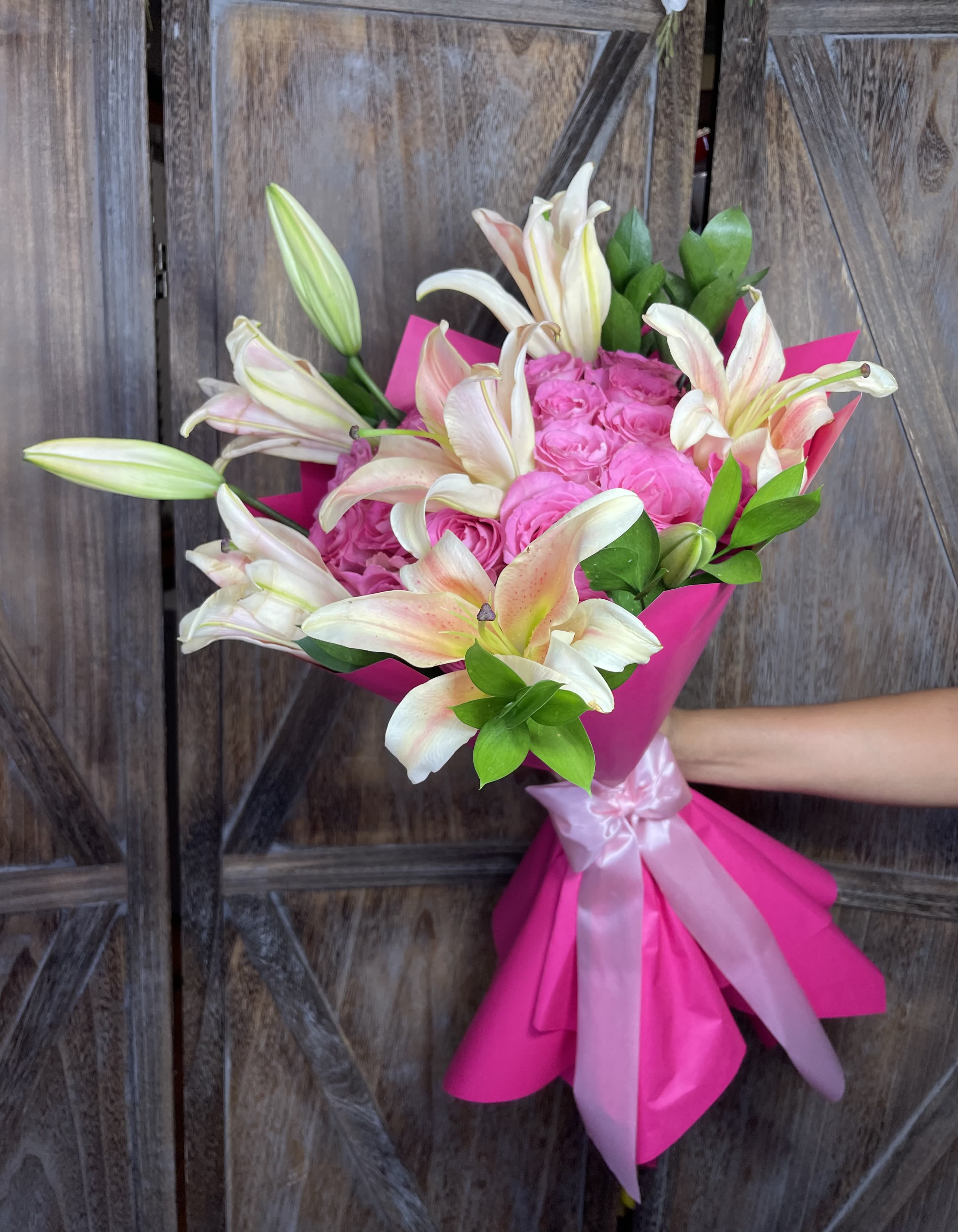 Pink rose bouquet with white lilies wrapped in bright pink paper
