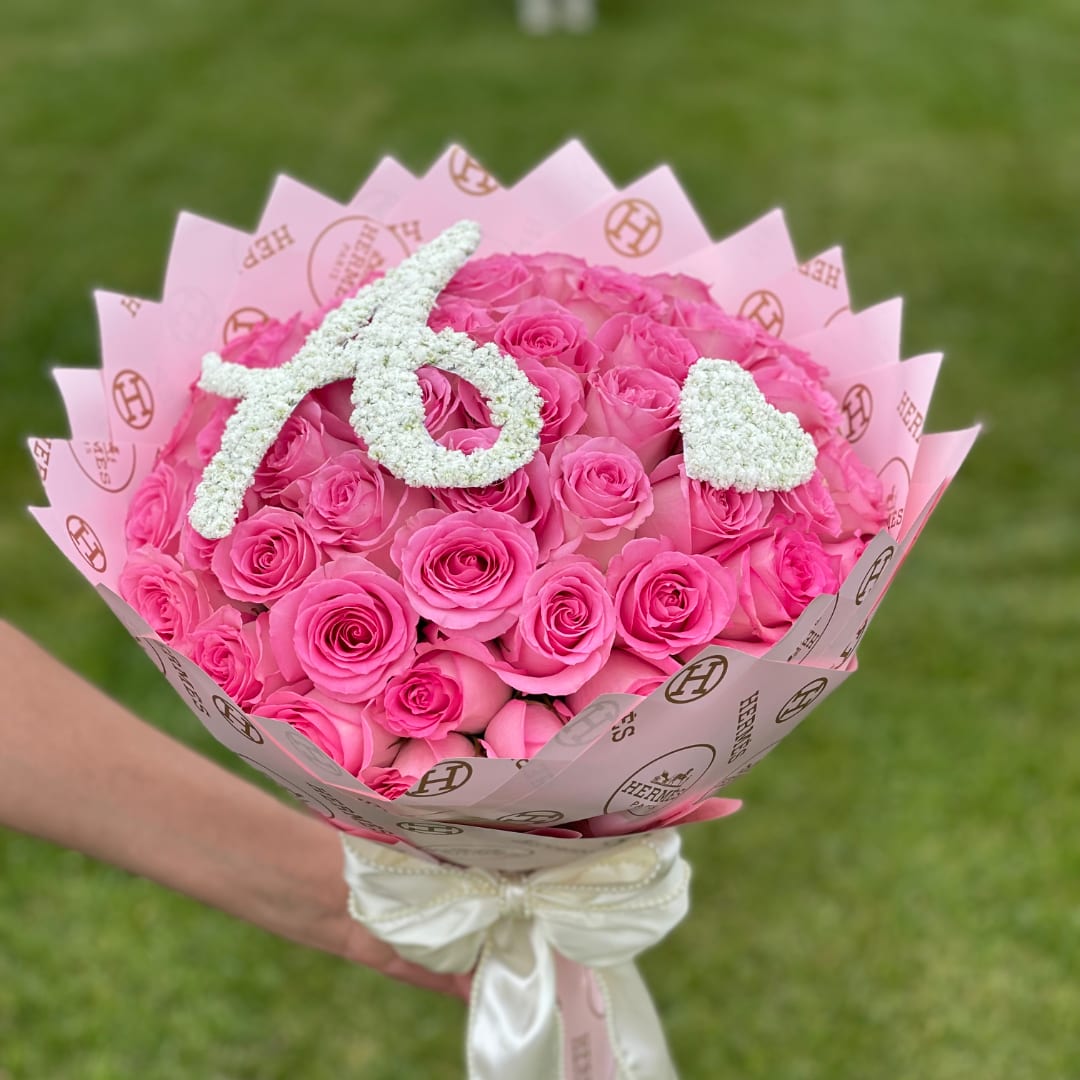 Pink rose bouquet with white floral letters and a satin ribbon wrap