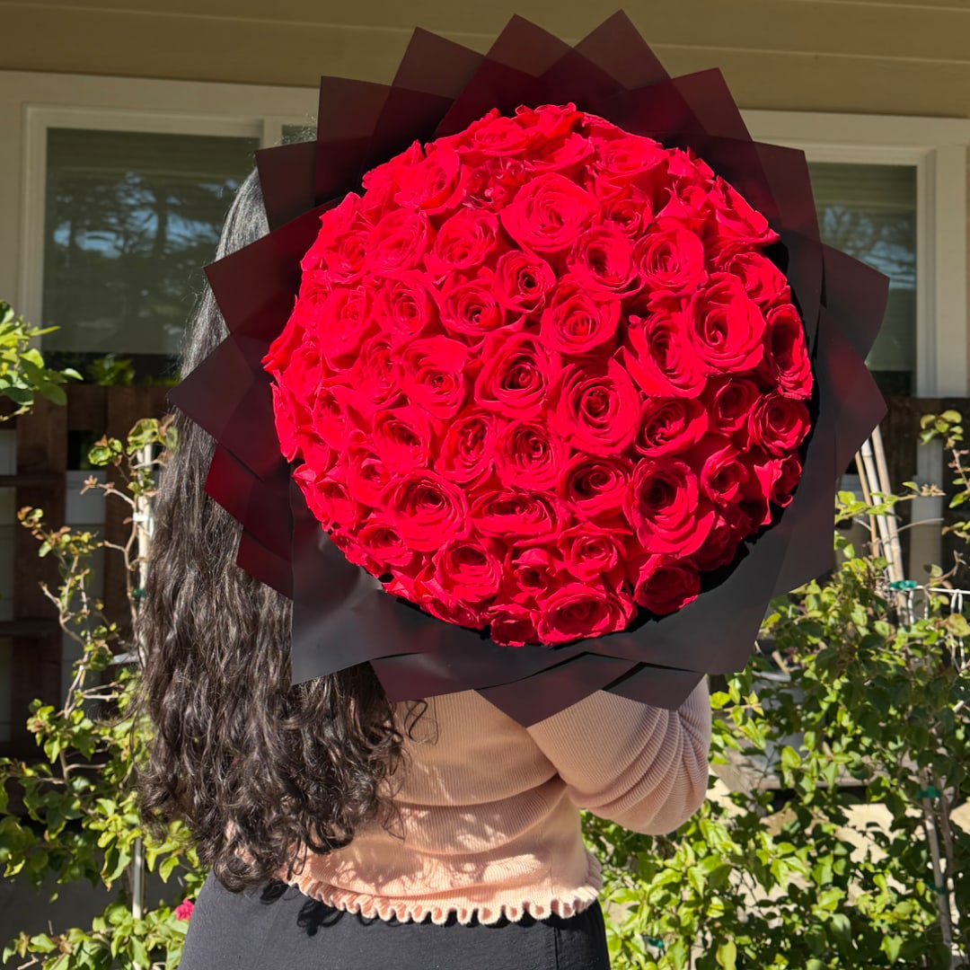 Large round bouquet of red roses wrapped in dark paper