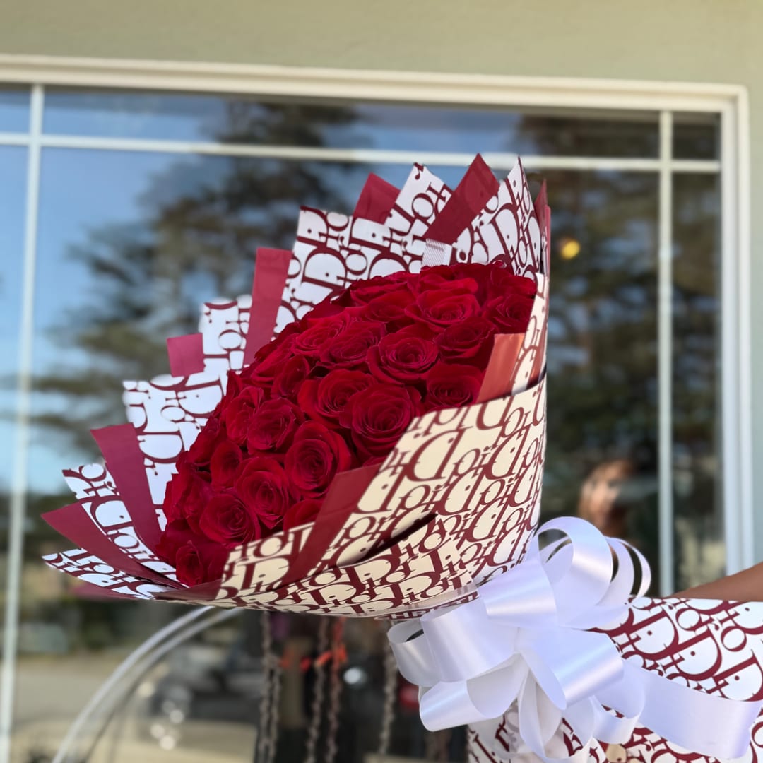 Bouquet of red roses wrapped in patterned paper with a white ribbon