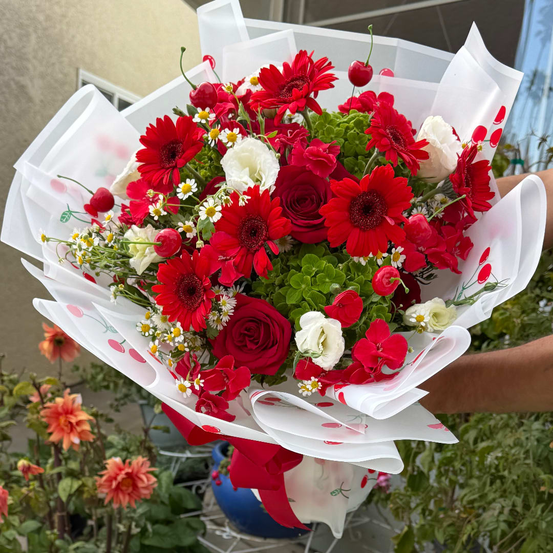 Red and white mixed bouquet wrapped in white paper with a red ribbon
