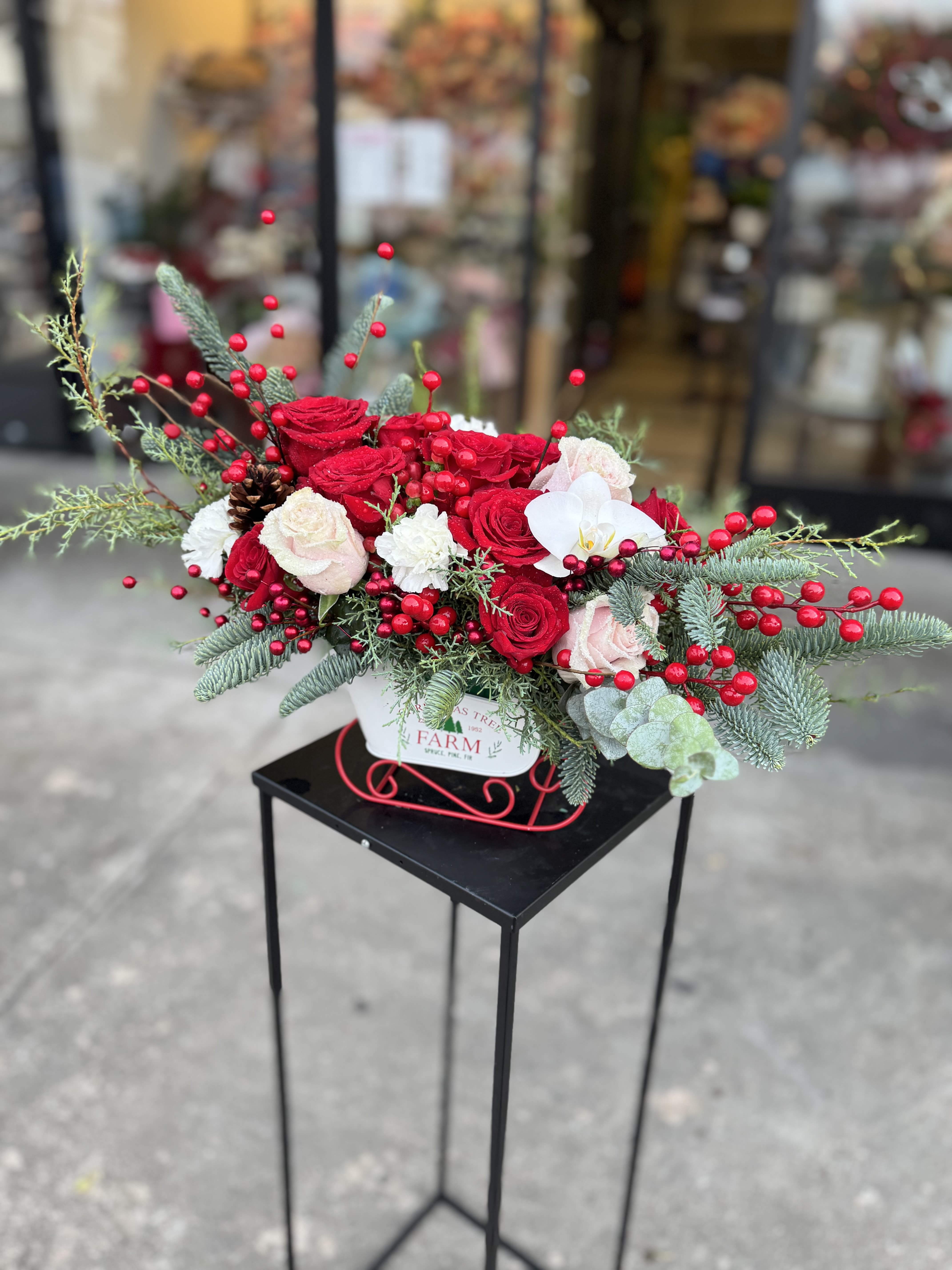 Red and white rose arrangement with berries in a white container