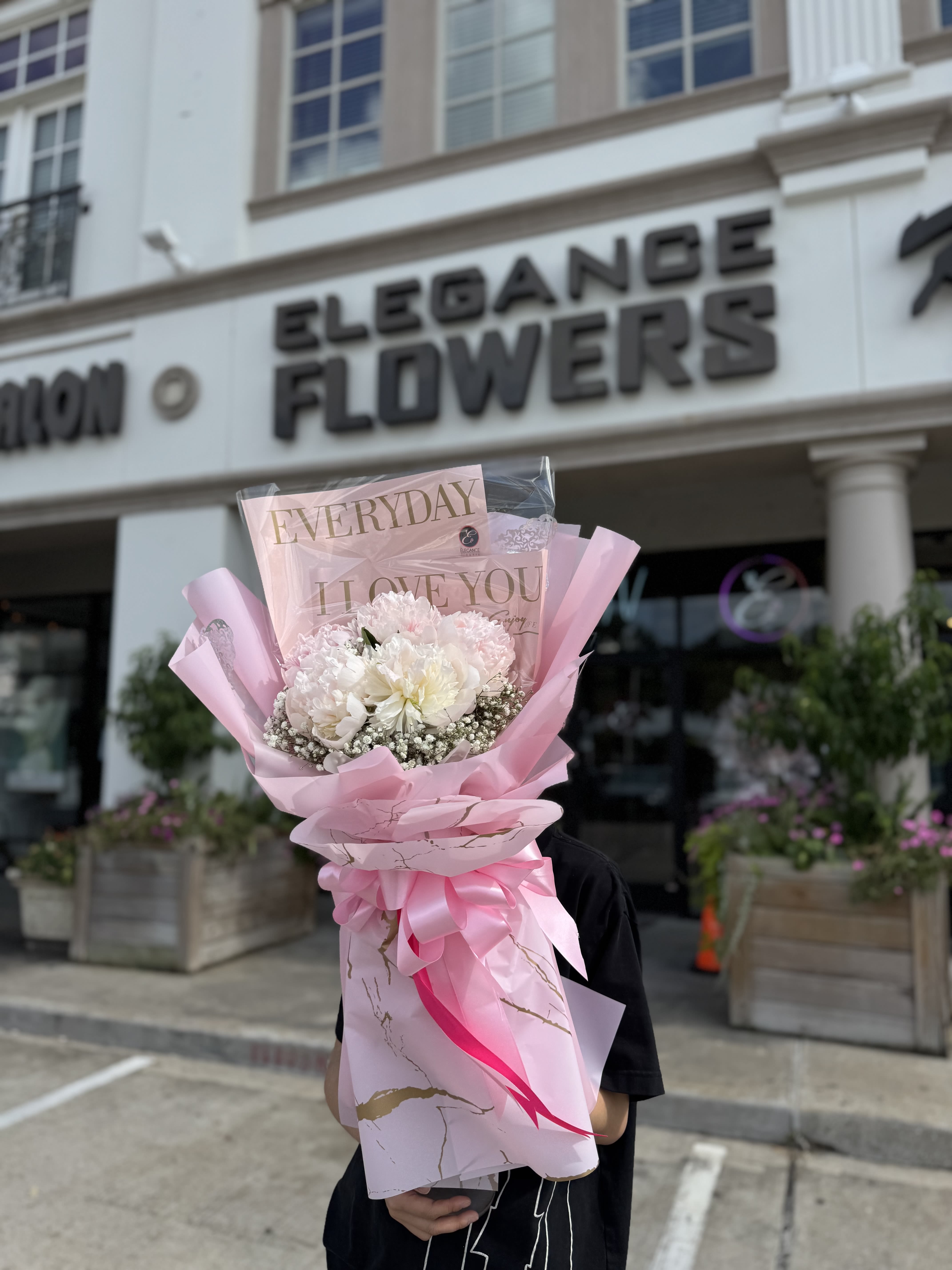Pink-wrapped bouquet of white and pale pink flowers