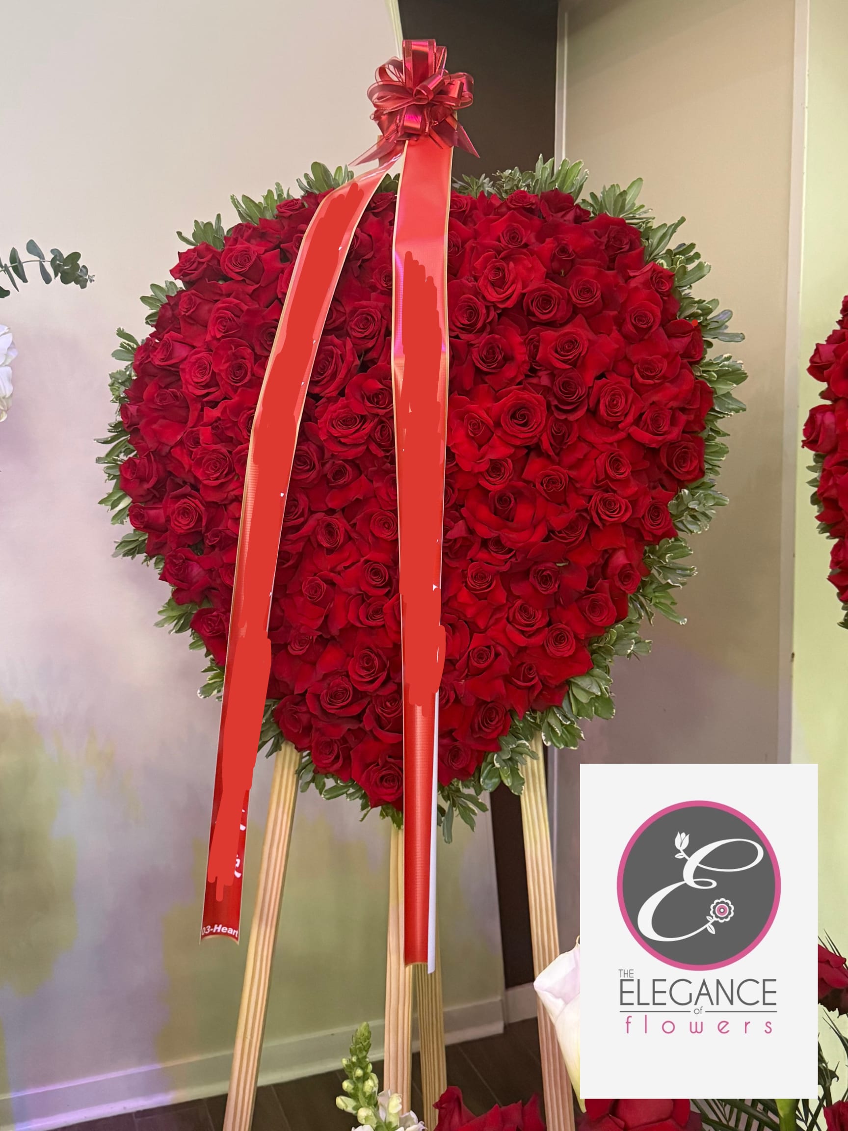 Heart-shaped red rose standing spray with a ribbon on an easel