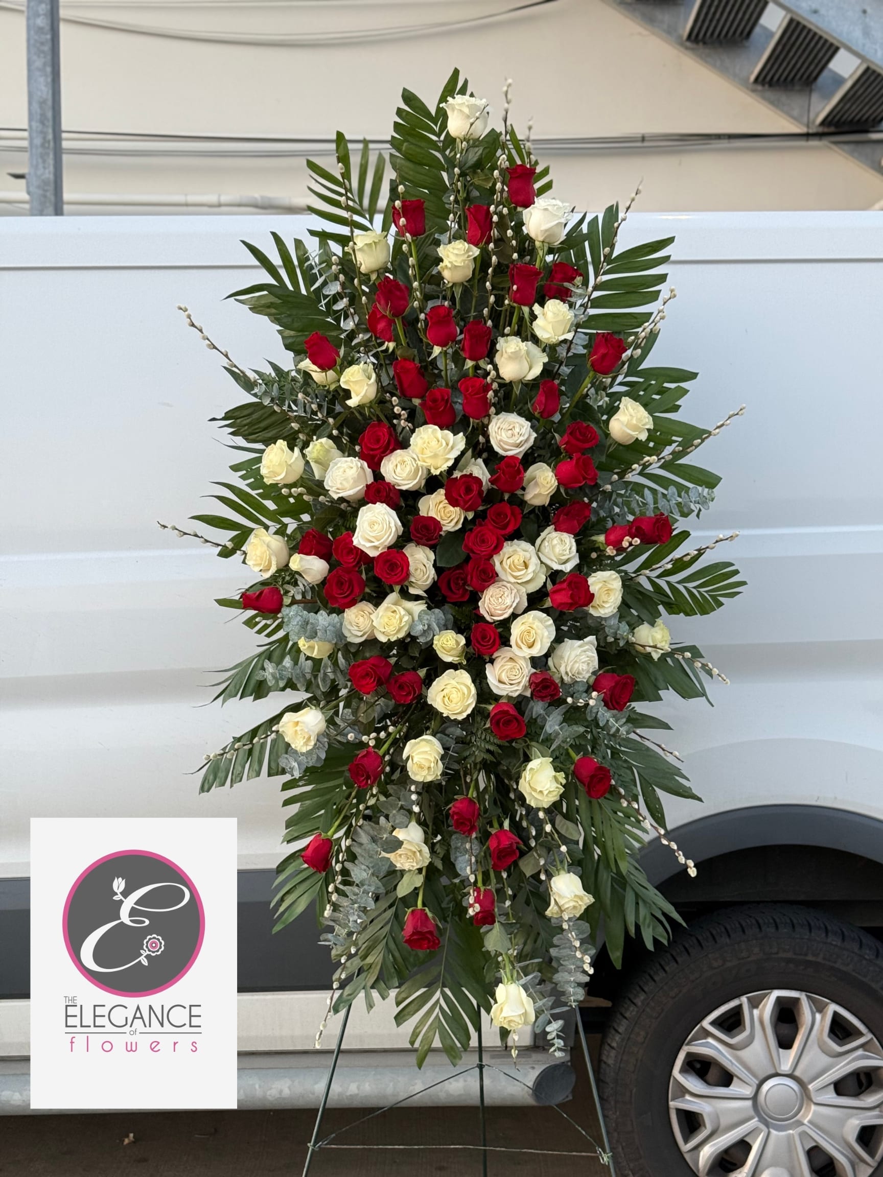 Standing spray of red and white roses with palm fronds