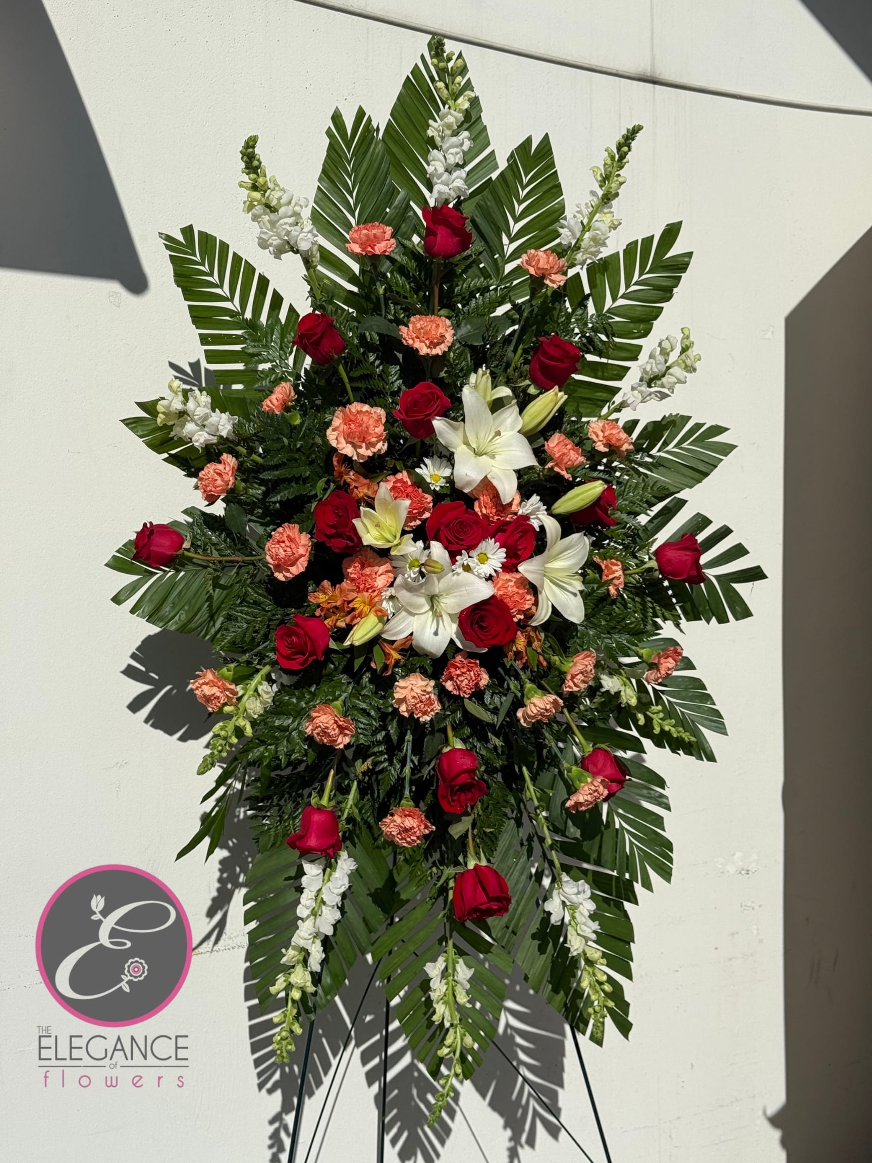 Standing floral spray with red roses, white lilies, and peach carnations