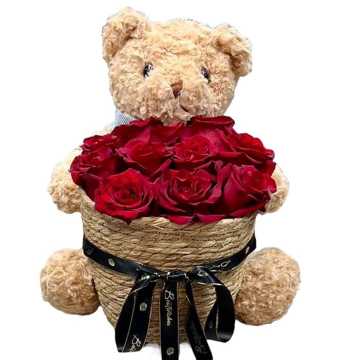 Teddy bear holding a basket of red roses