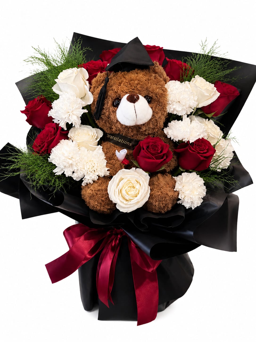 Forever Proud Graduation Bouquet - A playful, proud centerpiece for graduation celebrations: this flower arrangement pairs classic red and white roses with soft white carnations around a cuddly brown teddy bear wearing a black graduation cap, making it an ideal graduation bouquet to congratulate a new grad. The bold contrast of glossy black wrapping paper and deep burgundy satin ribbon gives the presentation a formal, gift-like polish while the vibrant blooms keep the mood joyful - the kind of gift that announces "you did it" with warmth.  The arrangement features red roses and white roses accented by white carnations and lush green foliage, all gathered around the teddy bear so the plush keepsake is front-and-center. Everything is wrapped in high-shine black paper and finished with a deep burgundy satin ribbon and a miniature graduation cap on the bear, creating a cohesive red, white, black, and green palette that reads celebratory and sophisticated.  Perfect for the graduate who deserves both a hug and a bouquet, this gift suits high school and college commencements or a congratulatory doorstep surprise. It arrives ready to display as a table centerpiece or keepsake photo prop; light misting of the stems and a fresh water source will keep the flowers looking their best for several days.