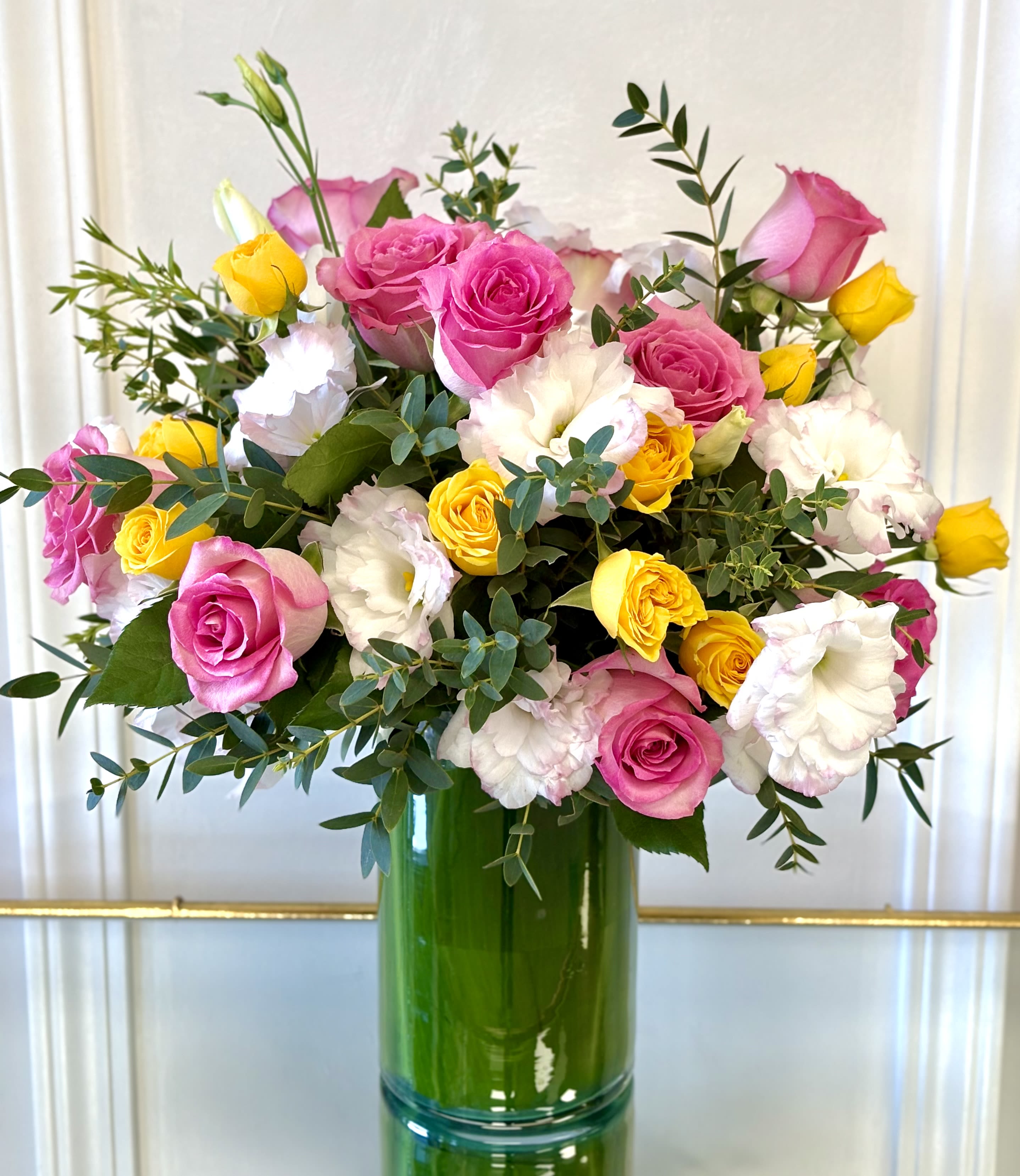 Pink Lemonade Blooms By VLM Flowers - A vibrant bouquet of pink roses, golden yellow spray roses, white lisianthus, and lush eucalyptus. This fresh arrangement brings together soft elegance and cheerful color, making it a perfect gift for birthdays, celebrations, or simply brightening someone's day.