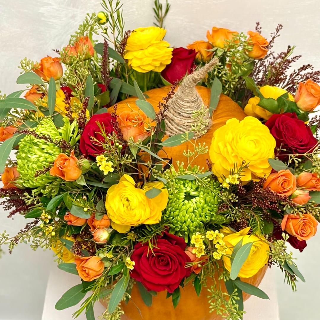 Bouquet of red, yellow, and orange flowers with a pumpkin centerpiece
