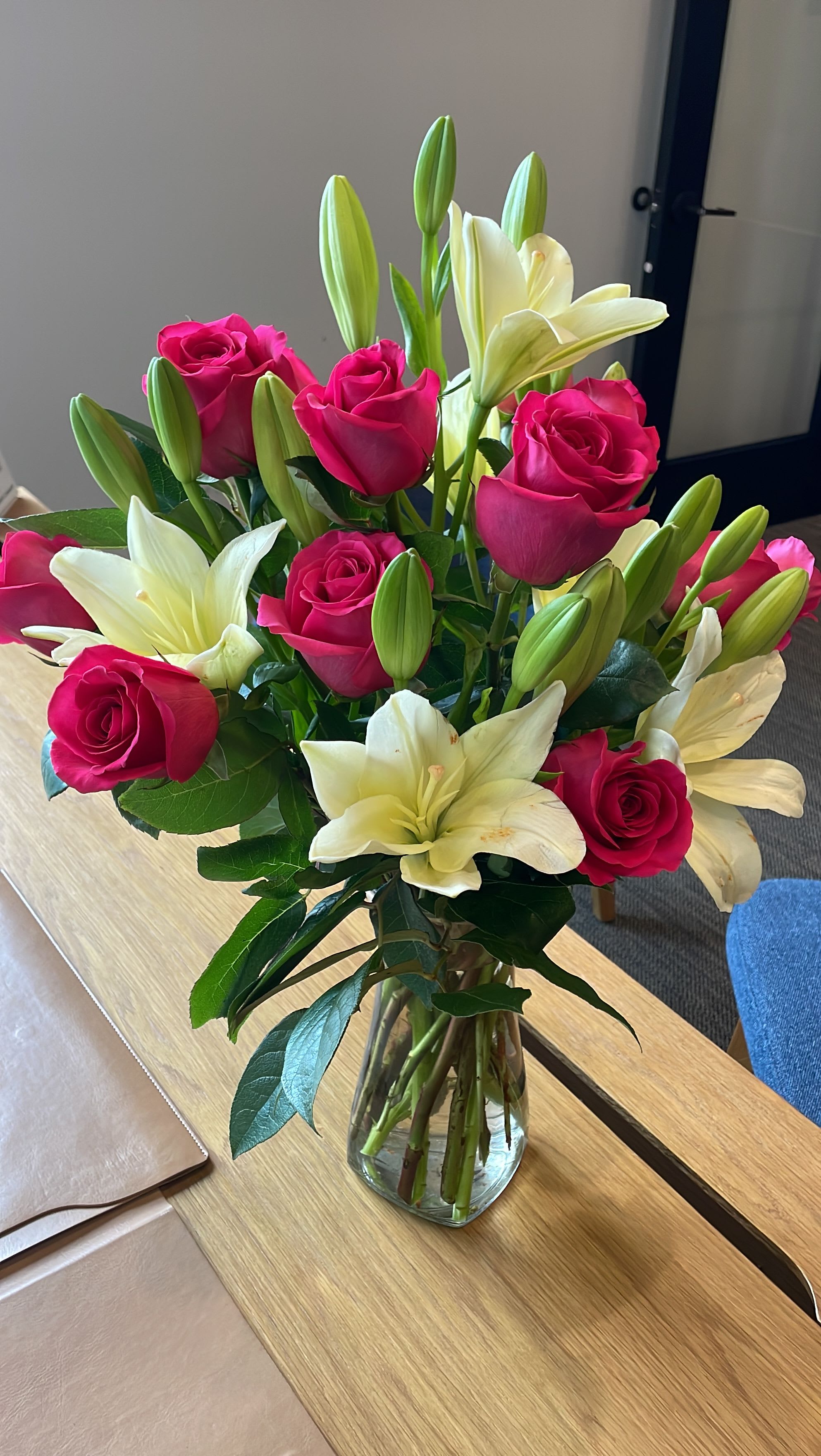 Pink roses and white lilies arranged in a clear glass vase