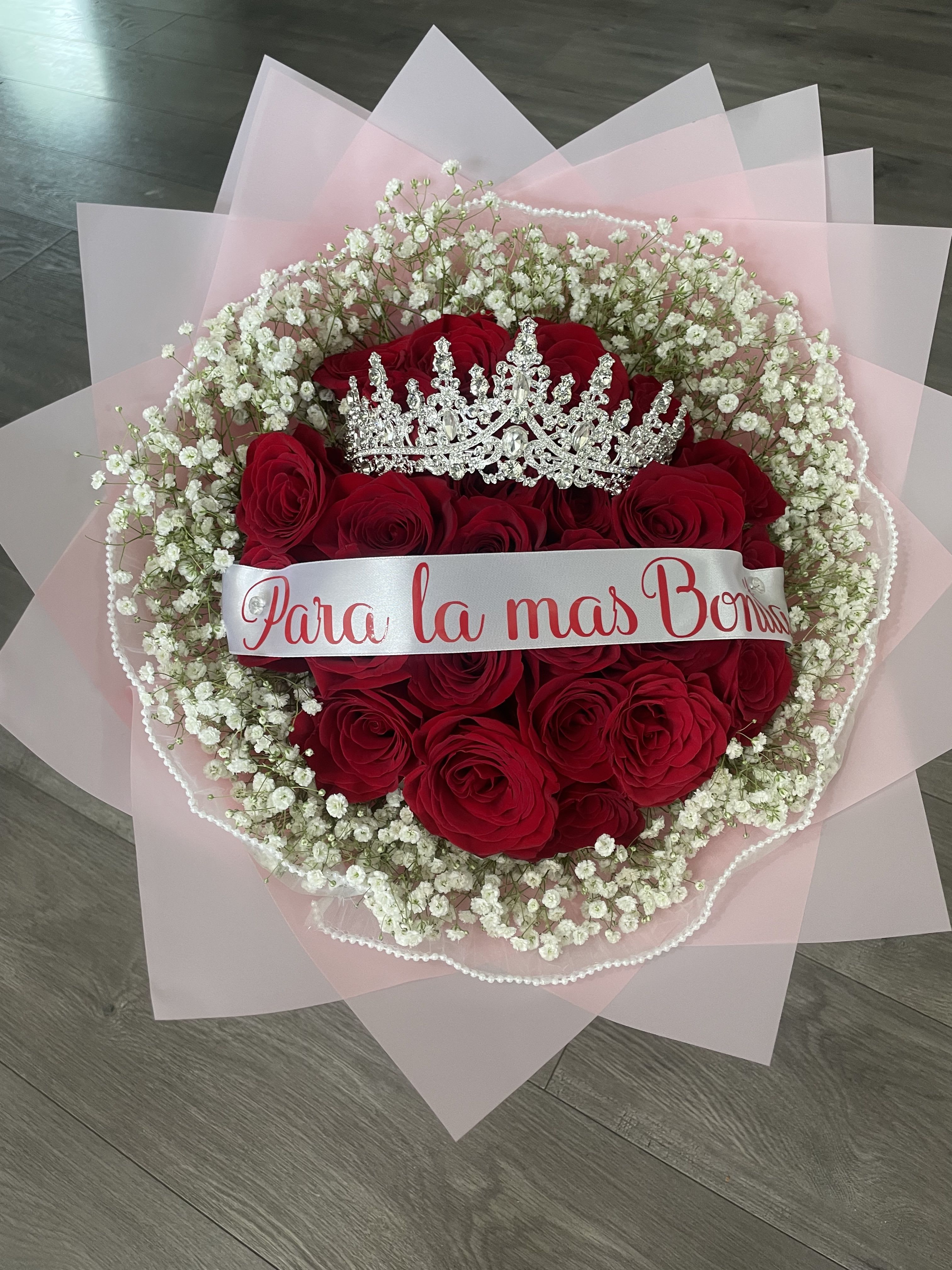 Enchanted Rose - A stunning arrangement of 24 red roses and baby's breath pearl ring, crowned with a sparkling tiara and wrapped in elegant pink paper. Finished with a satin ribbon that can get personalized with 2-4 words— perfect for making her feel like royalty.  Ideal for birthdays, anniversary , or any special occasion.