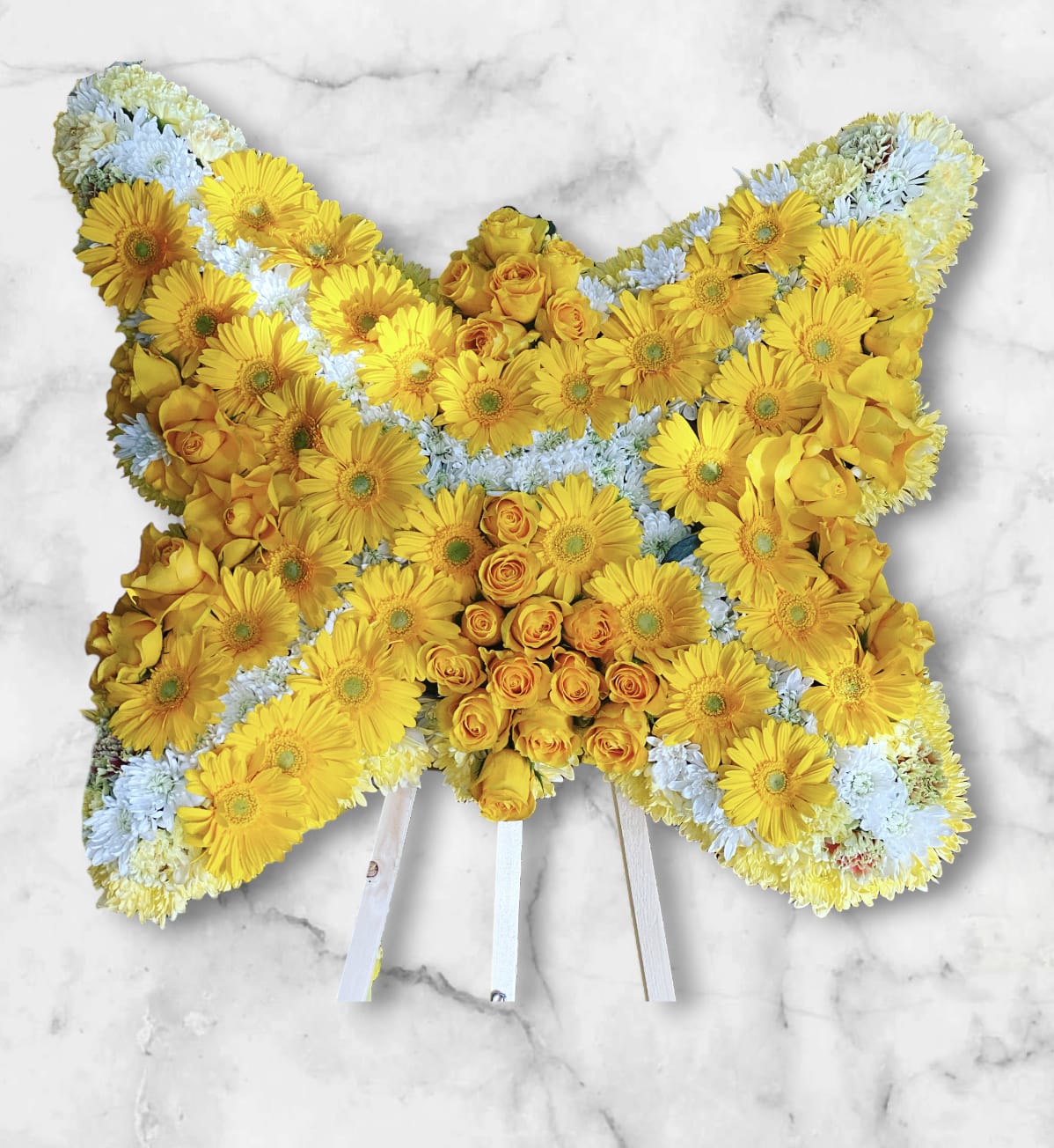 Butterfly Standing Funeral - A stunning butterfly shape, perfect for representing transformation, hope, and the continuation of life. With some white chrysanthemums, adding yellow roses which represent joy and caring of a loved one, and adding  yellow gerbera daisies to put the look together. 