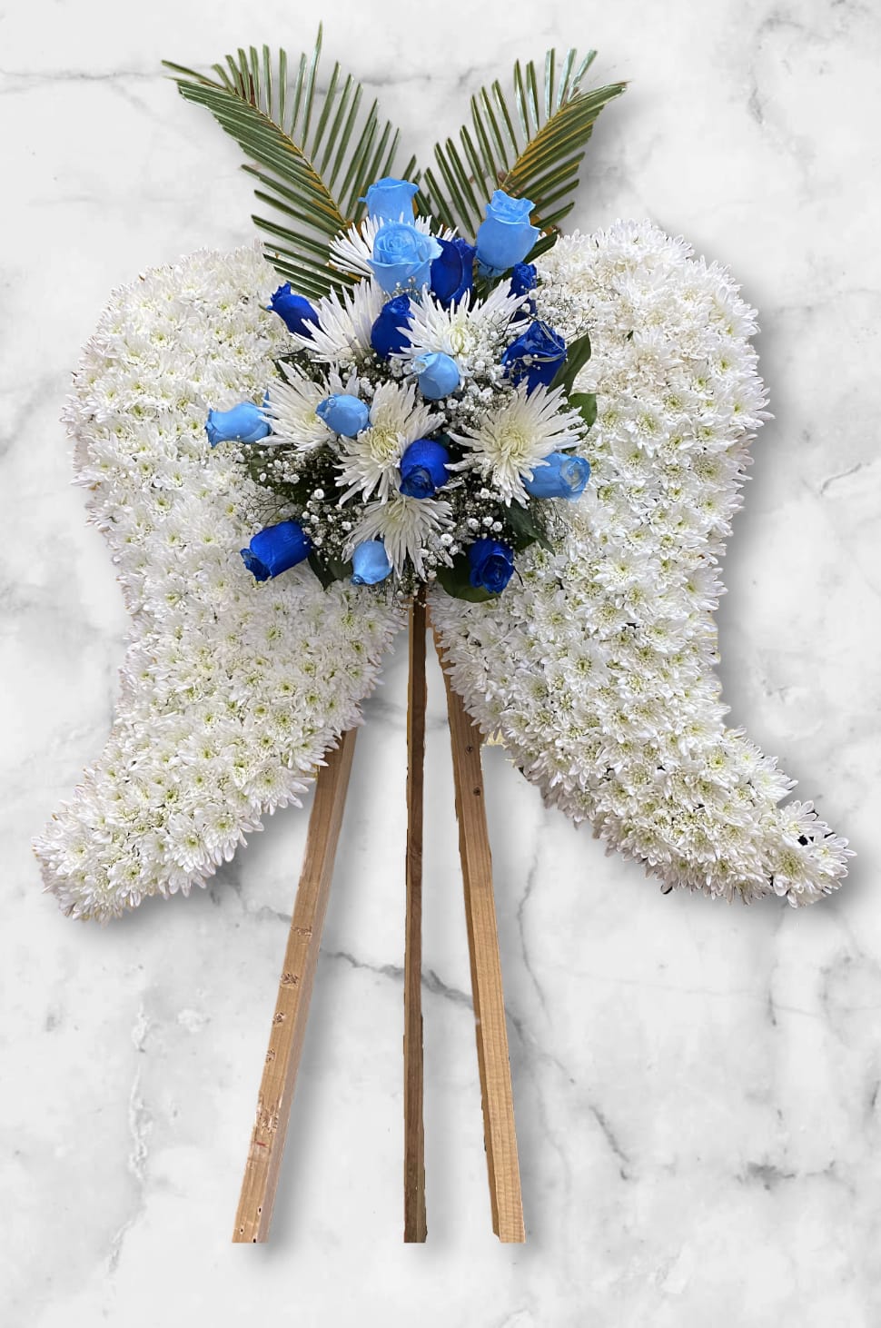 Medium Angel Wings Funeral  - The arrangement is elegantly shaped into angel wings, featuring a base of white chrysanthemums. The center is adorned with light blue and royal blue roses, complemented by delicate greenery and white spider mums.