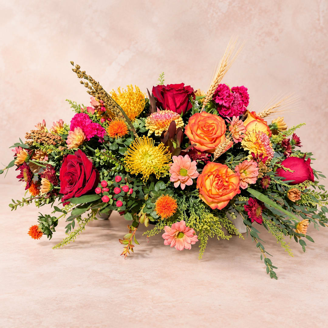 Low floral arrangement with red and orange roses and mixed blooms