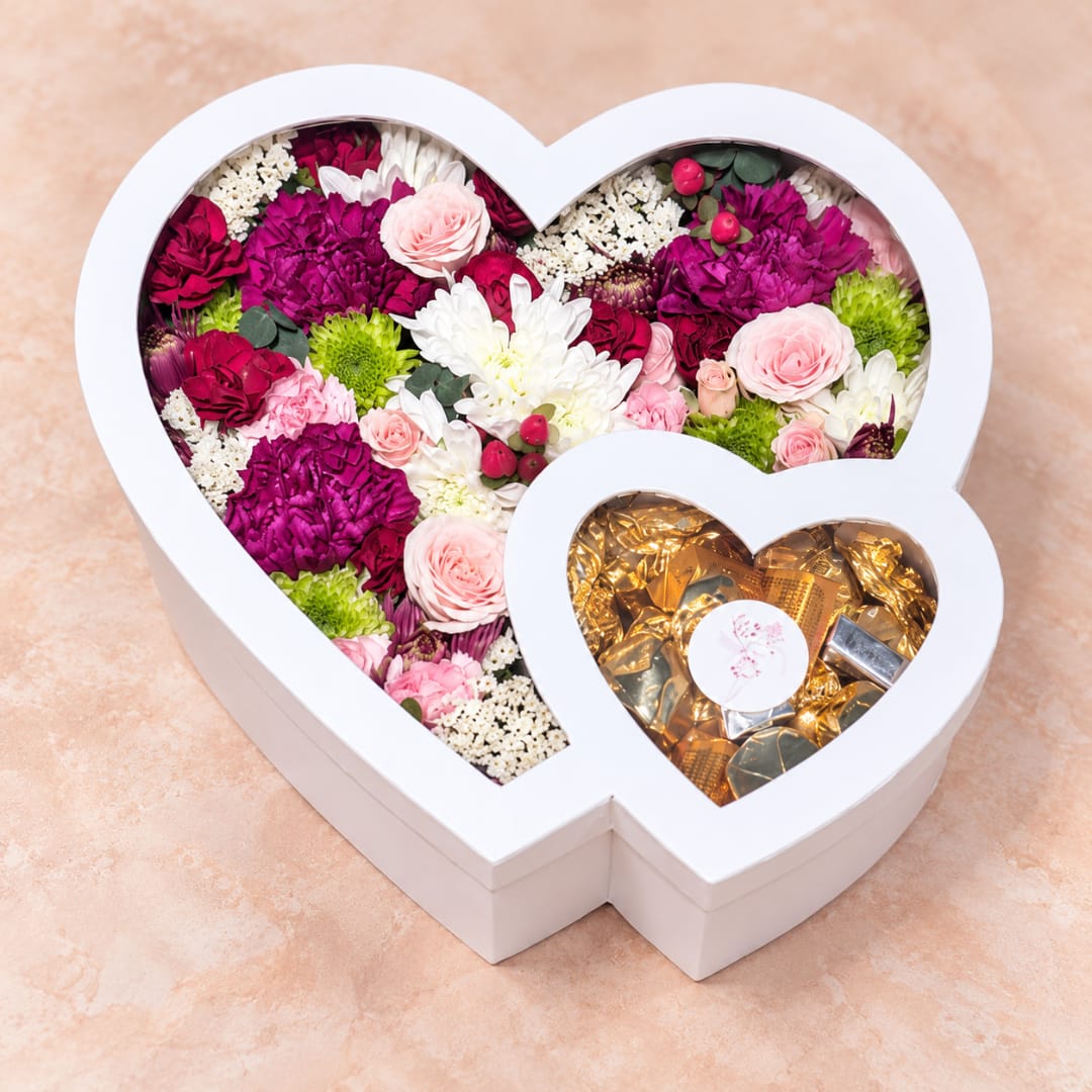 Heart-shaped flower box with pink, white, and magenta blooms and gold chocolates