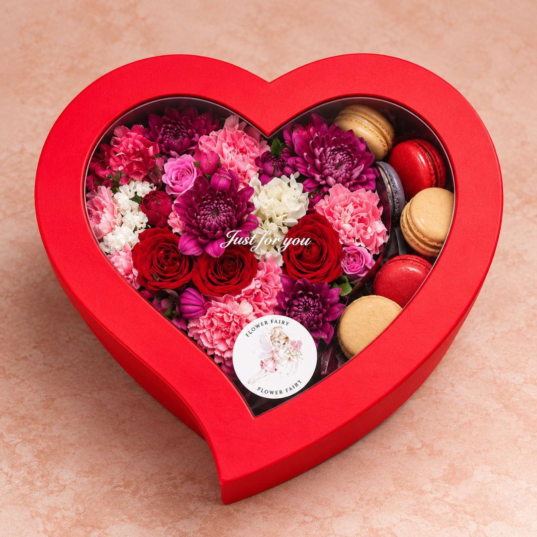 Heart-shaped gift box with red, pink, and purple flowers and macarons