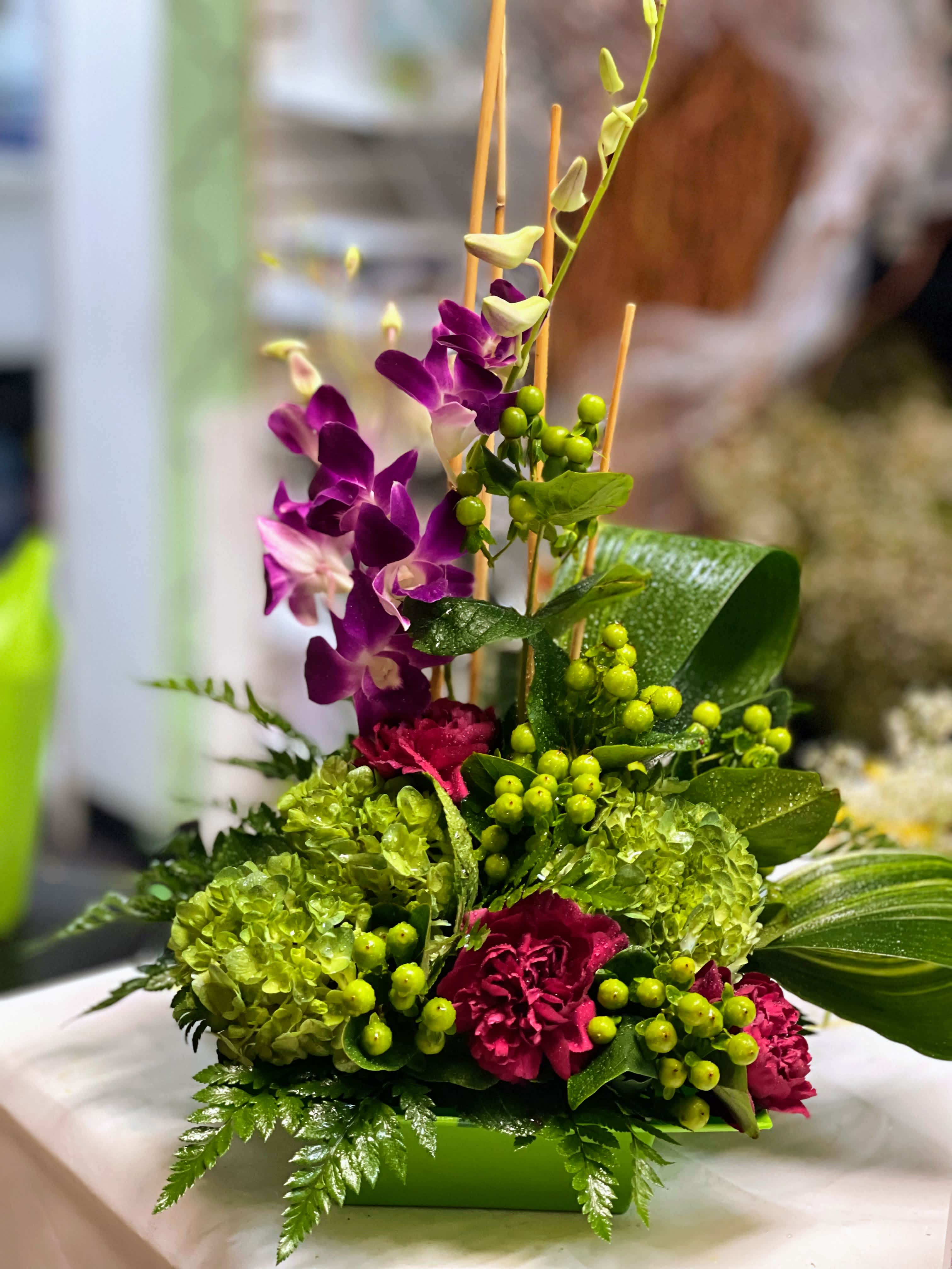 Purple orchids and green hydrangeas in a low rectangular container