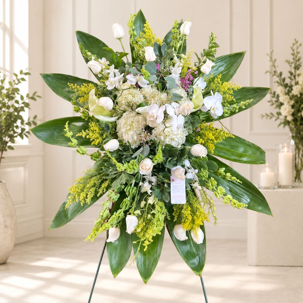 Large white floral standing spray with green foliage and yellow accents