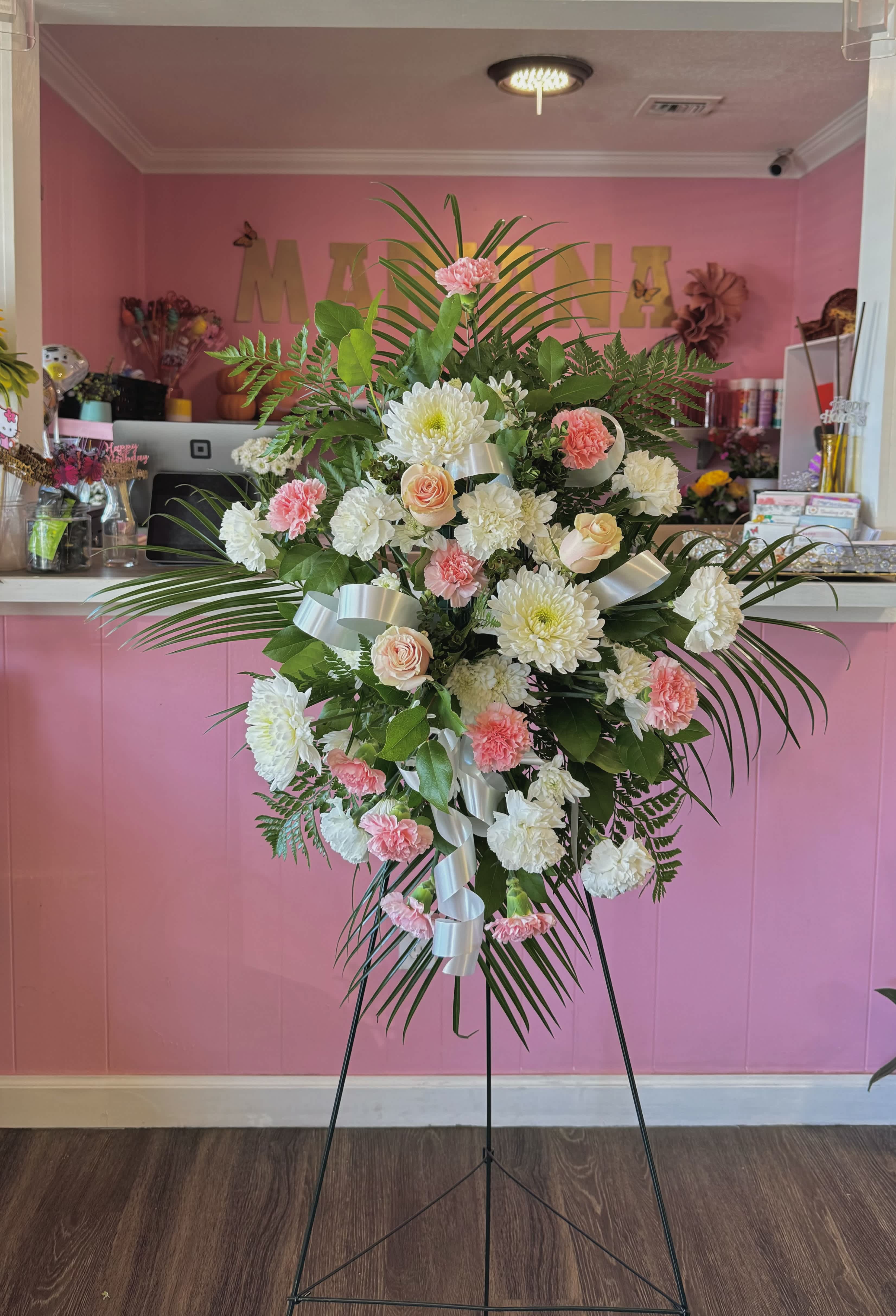 Standing floral spray with pink and white flowers on a metal easel