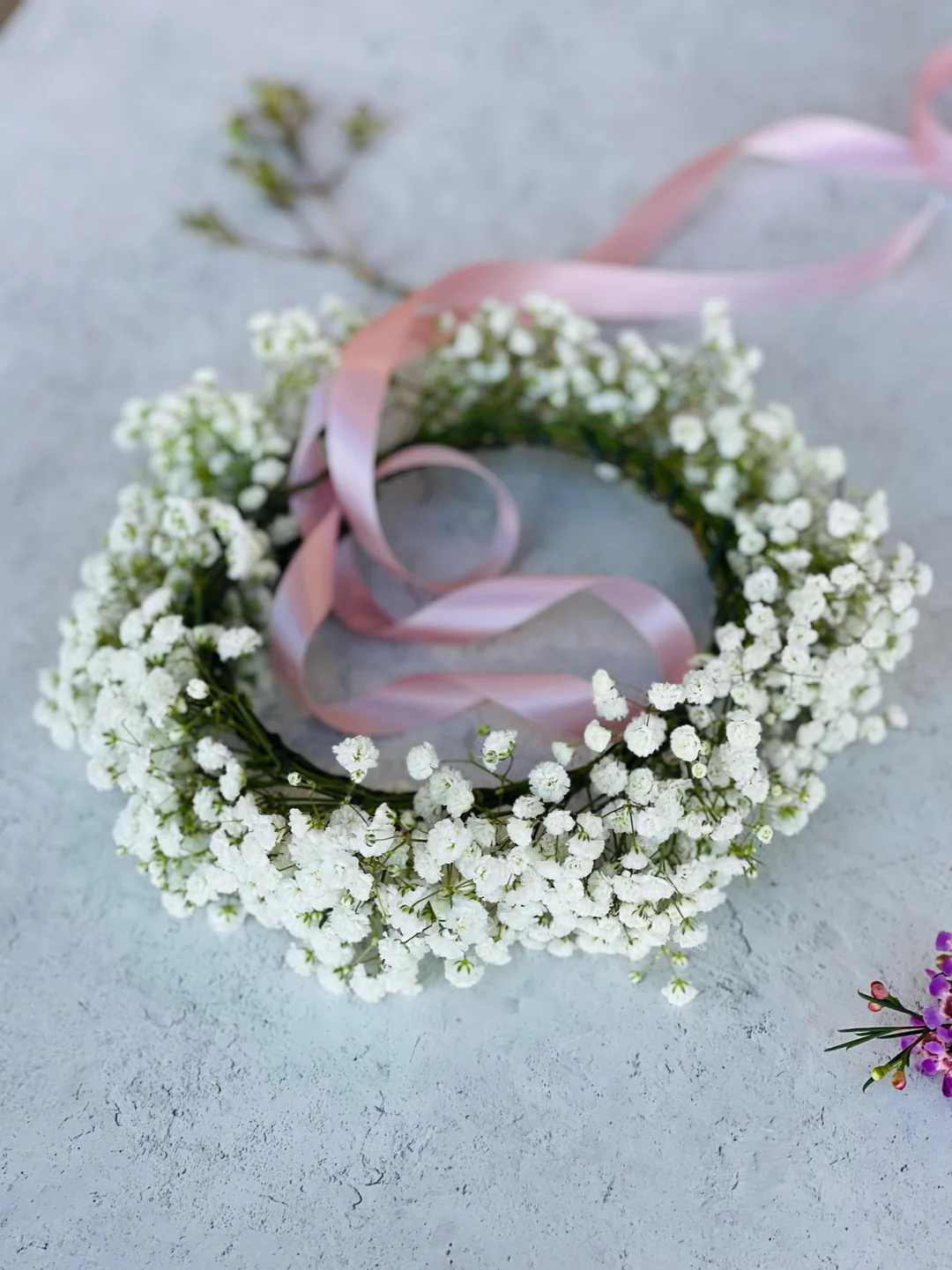 White baby's breath floral wreath with a pink ribbon