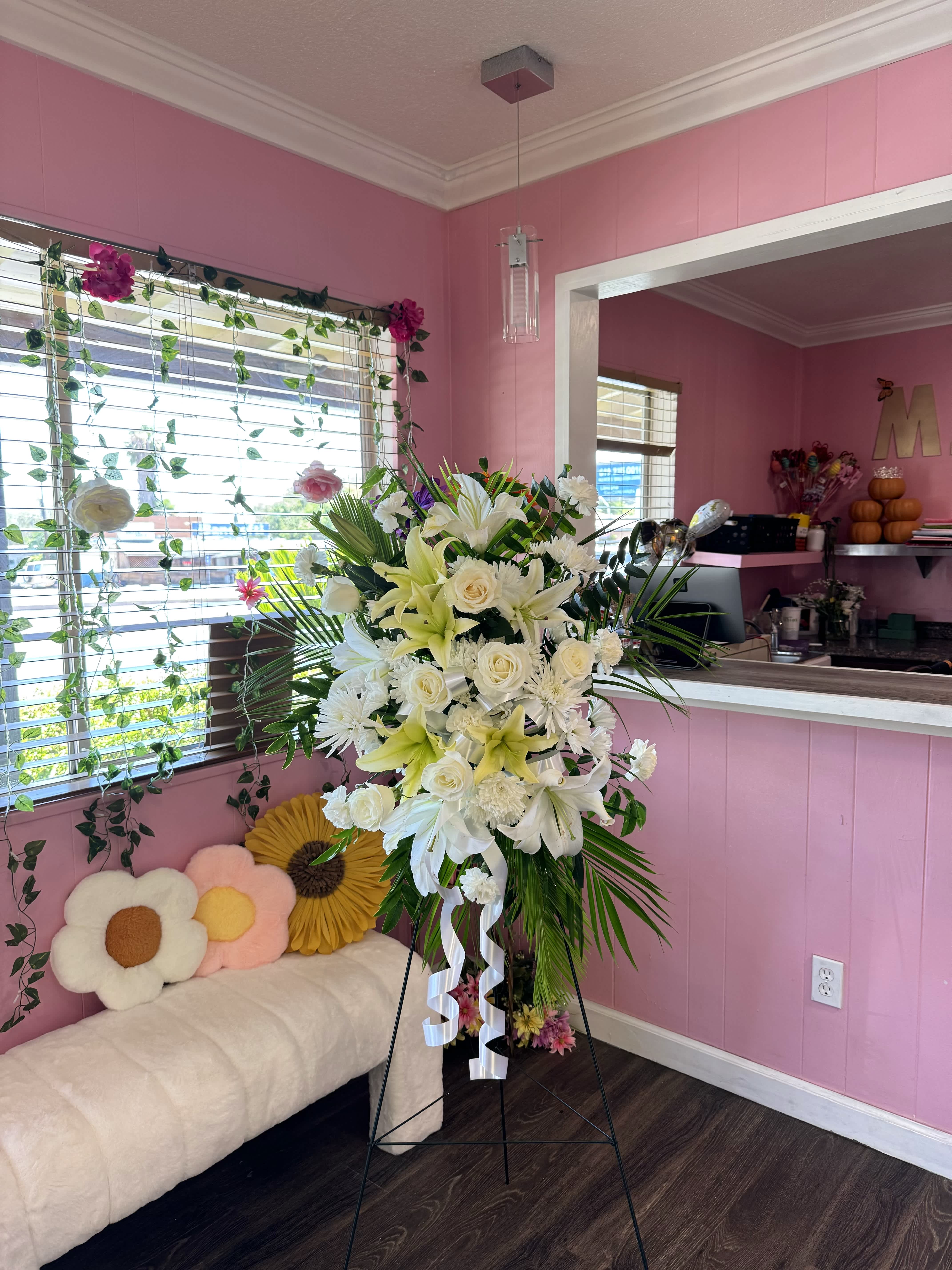 Tall white floral standing spray with lilies and roses on an easel