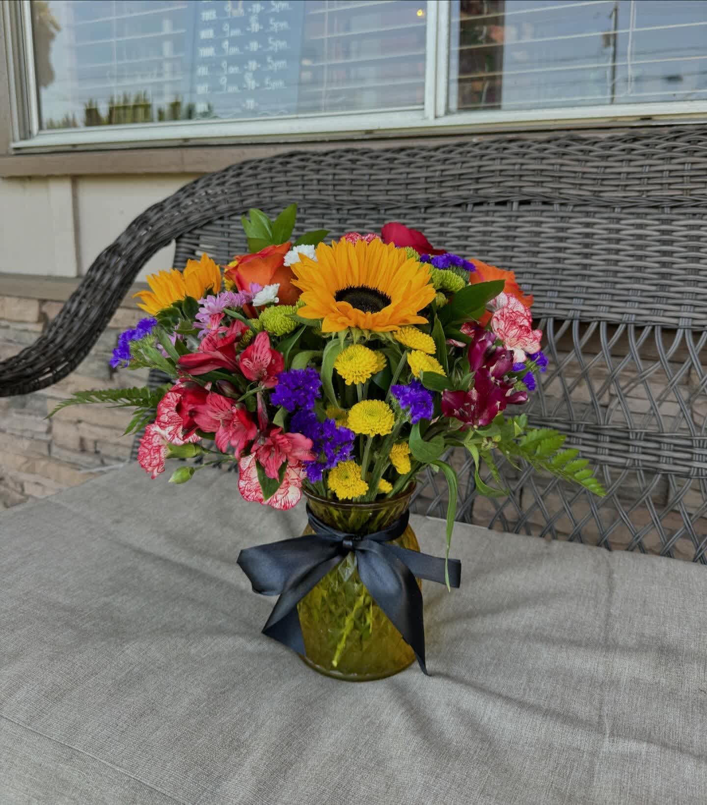 Colorful mixed bouquet in a glass vase with a dark ribbon